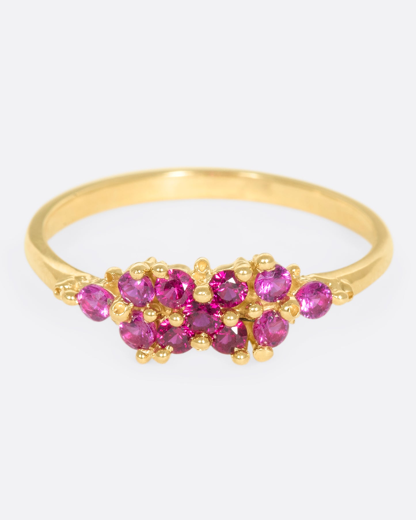 A yellow gold ring with a cluster of rubies arranged on the face. Shown from the front.