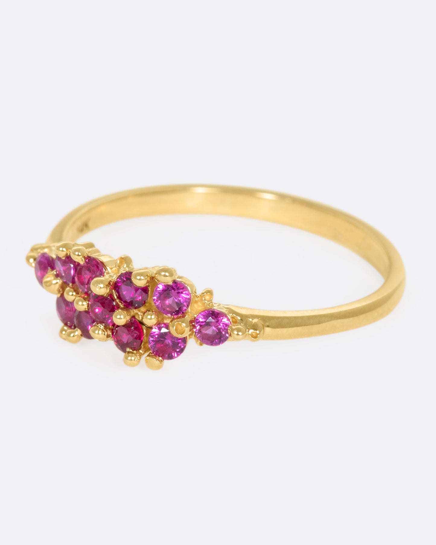 A yellow gold ring with a cluster of rubies arranged on the face. Shown from the side.