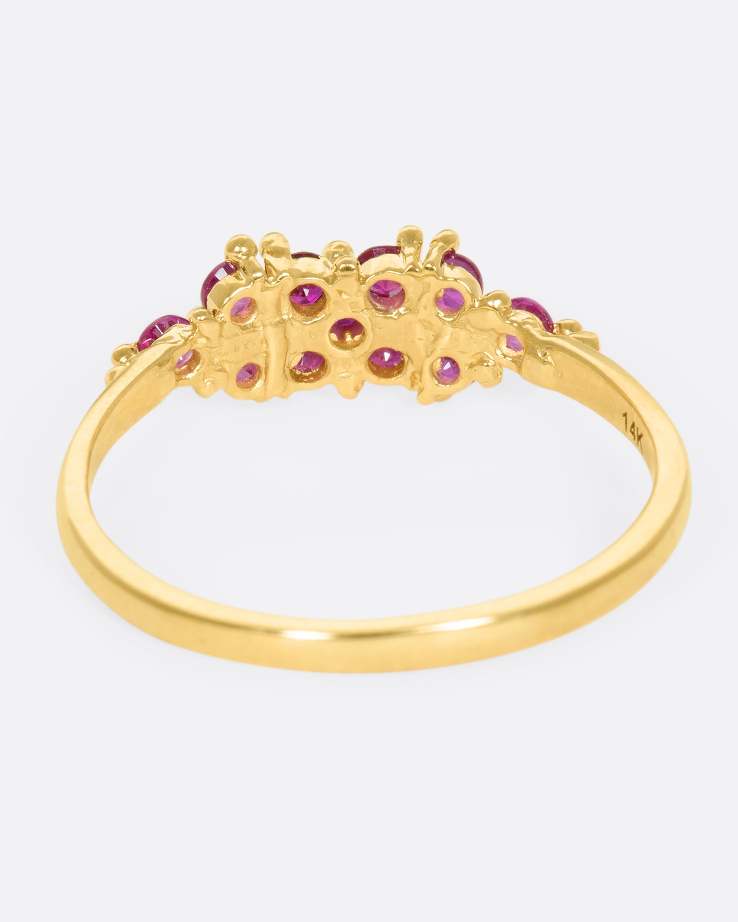 A yellow gold ring with a cluster of rubies arranged on the face. Shown from the back.