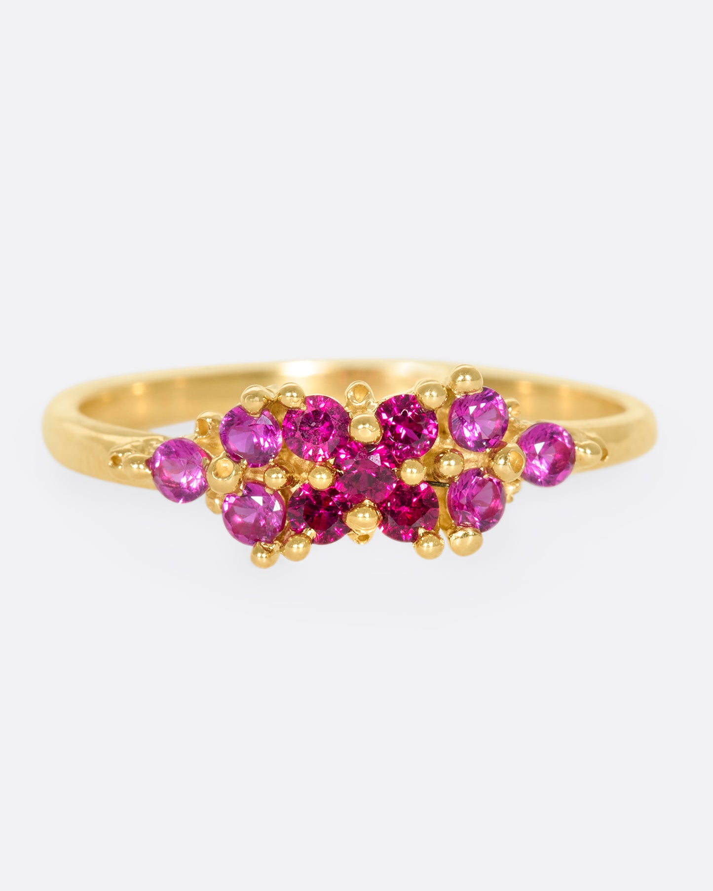 A yellow gold ring with a cluster of rubies arranged on the face. Shown from the front.