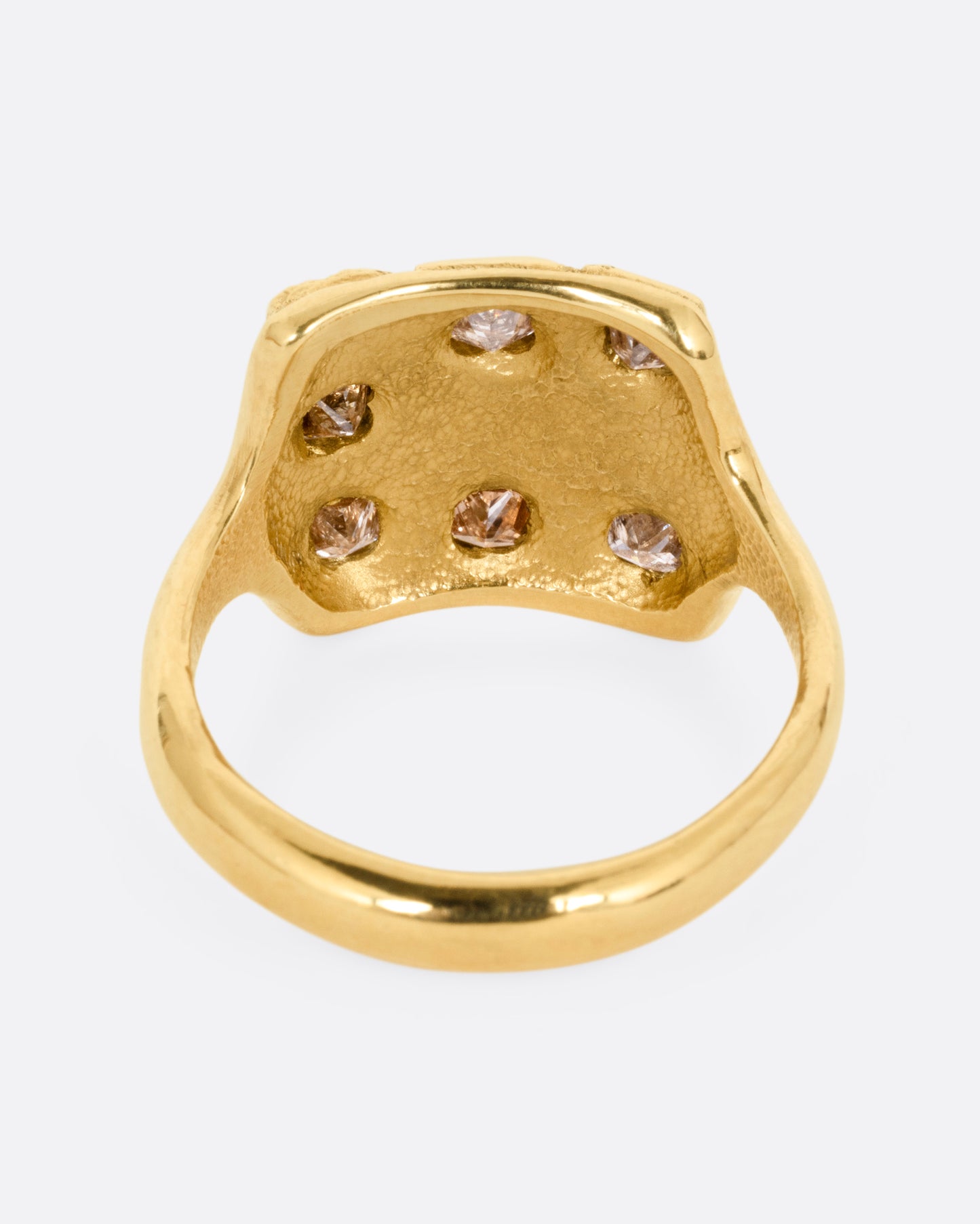 A yellow gold ring with princess cut brown diamonds and raised textural squares across its broad face. Shown from the back.