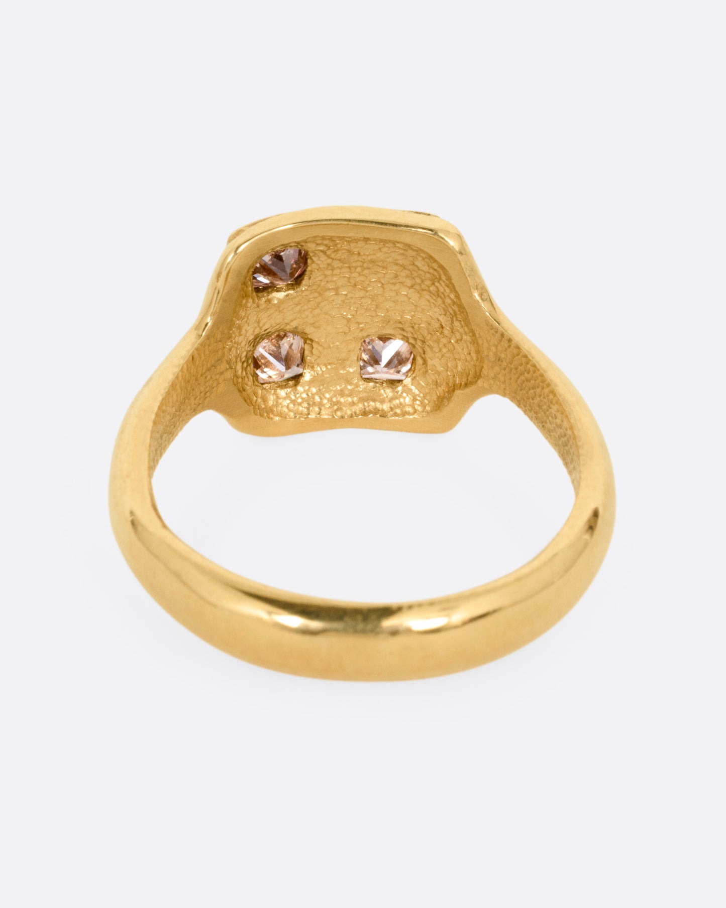 A yellow gold ring with three square diamonds on its square face, shown from the back.