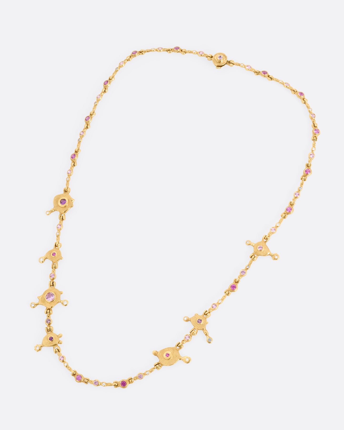 A yellow gold necklace with purple sapphires and diamonds set in handmade stations, shown from the front.