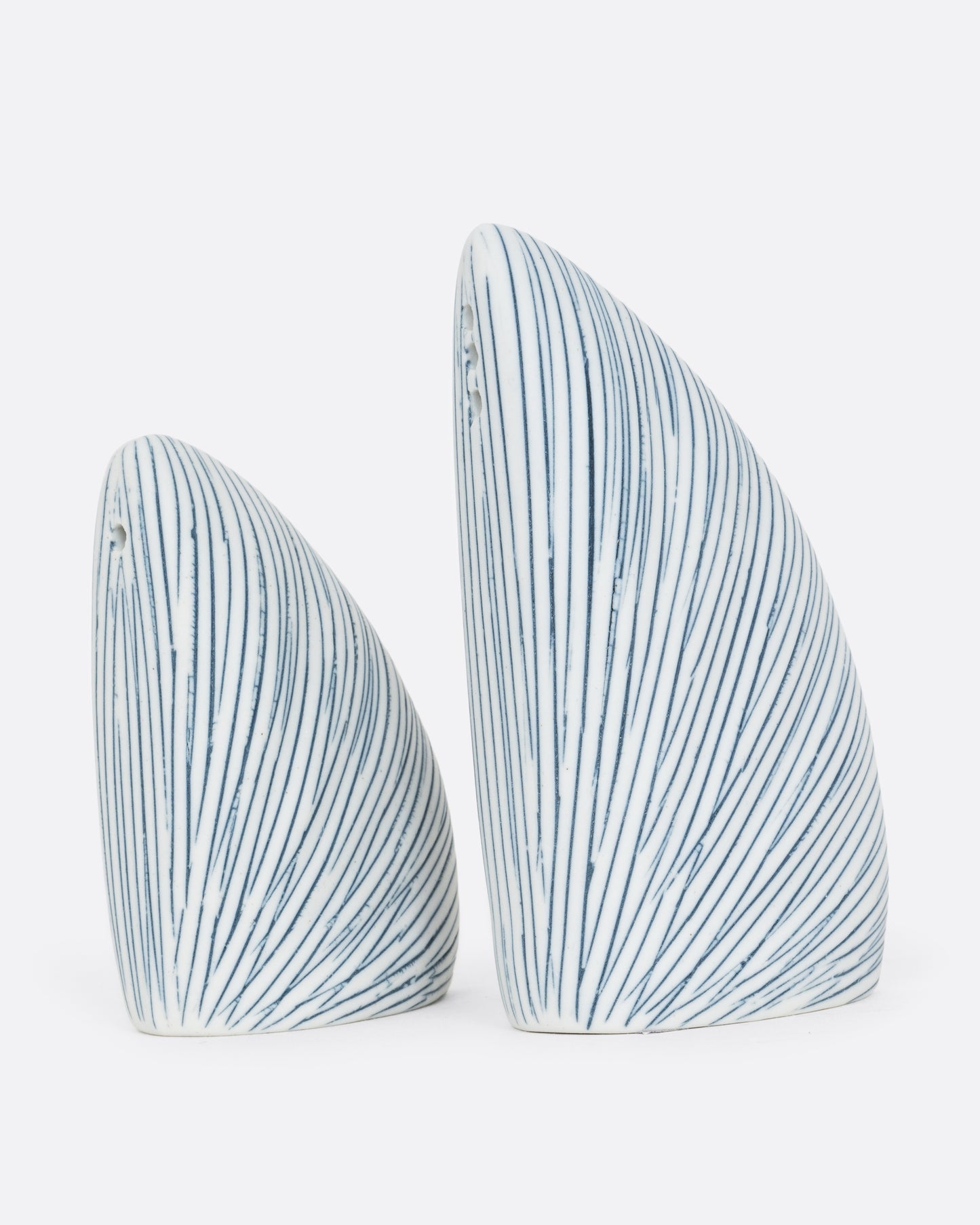A pair of triangular white and blue striped pair of salt and pepper shakers. One shaker is shorter. Shown from the side.