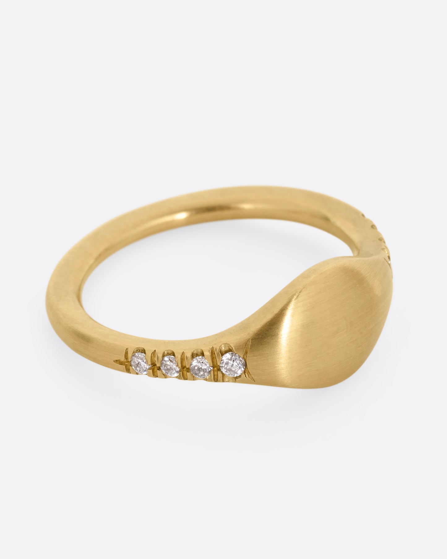 A yellow gold signet ring with diamonds on the shoulders. Shown from the side.