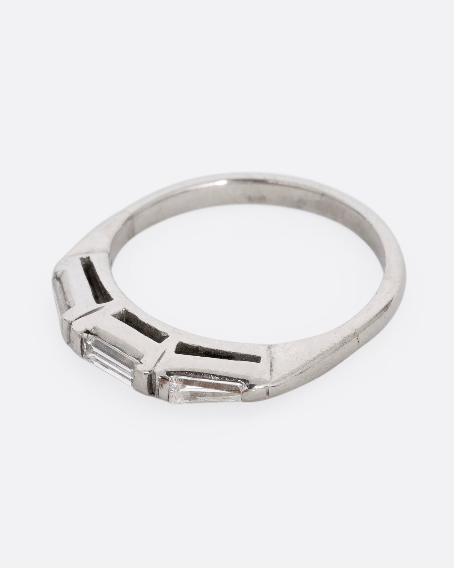 A platinum ring with three baguette diamonds. Shown from the side.