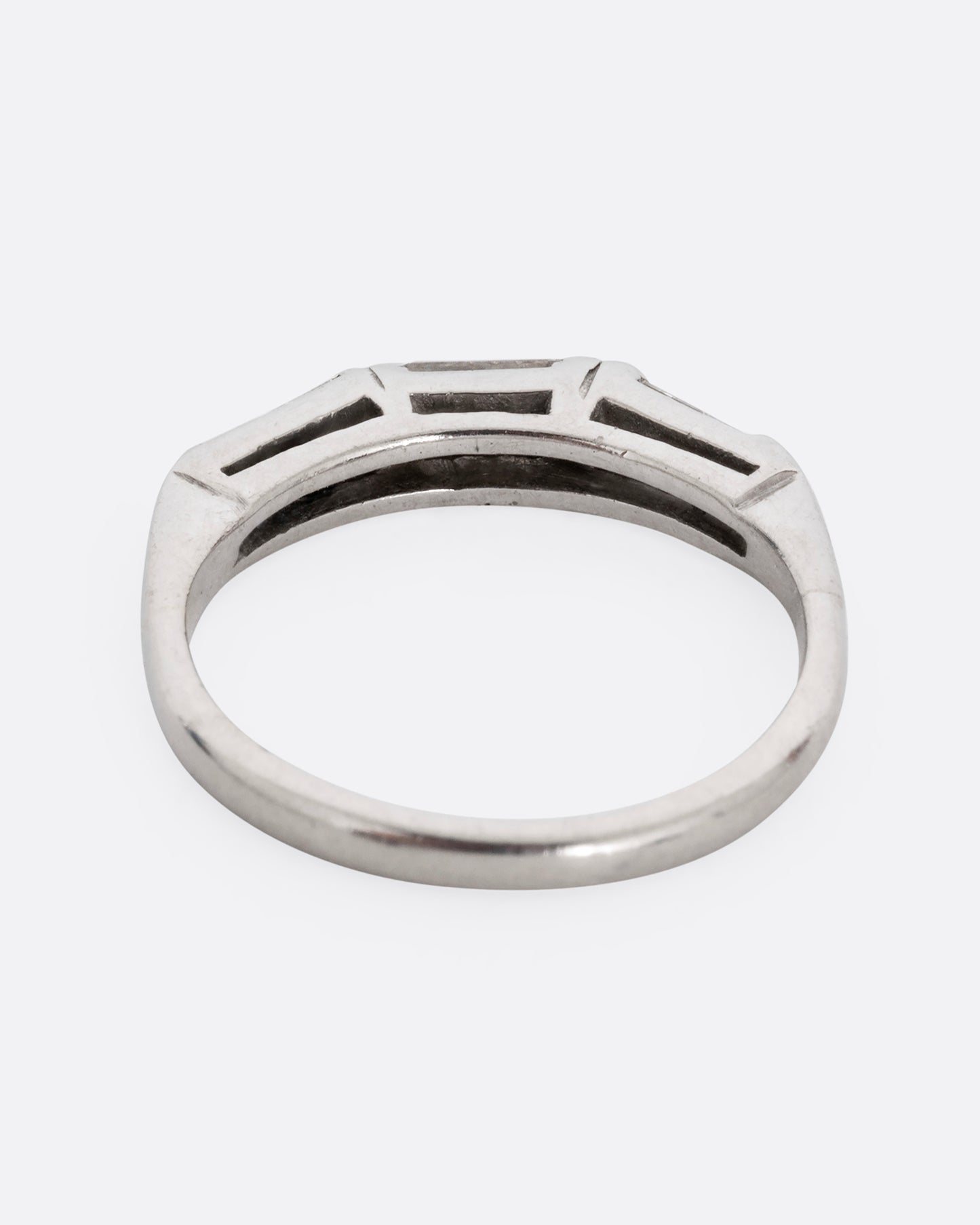 A platinum ring with three baguette diamonds. Shown from the back.