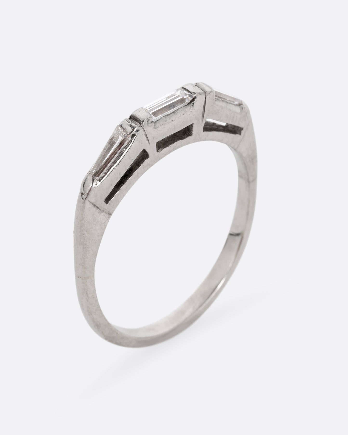 A platinum ring with three baguette diamonds. Shown standing up from the side.