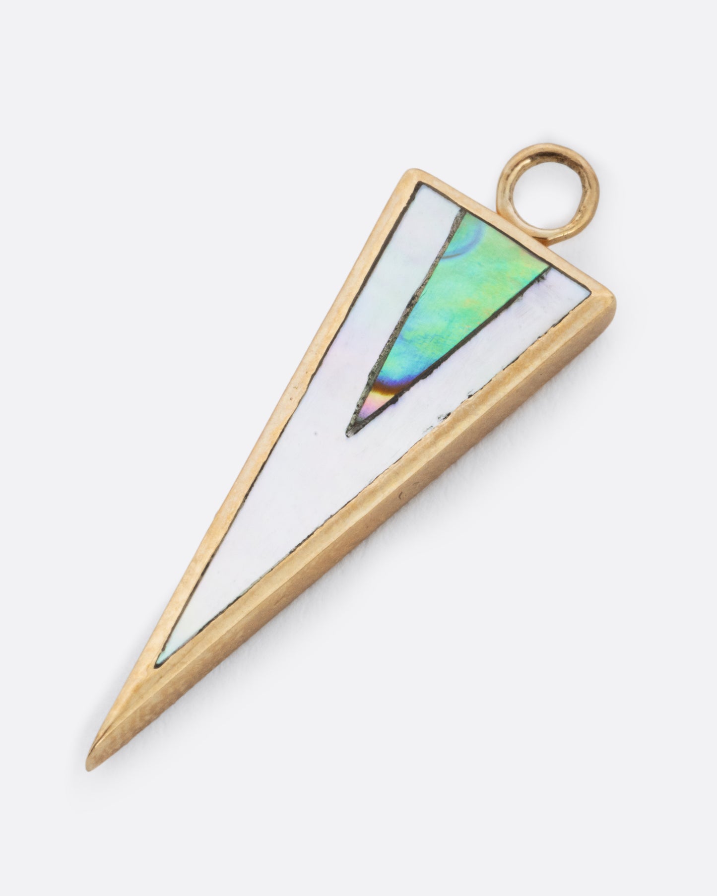 A yellow gold triangular dangle with the point facing down. It's inlaid with triangles of layered mother of pearl and abalone. Shown lying flat diagonally from the front.