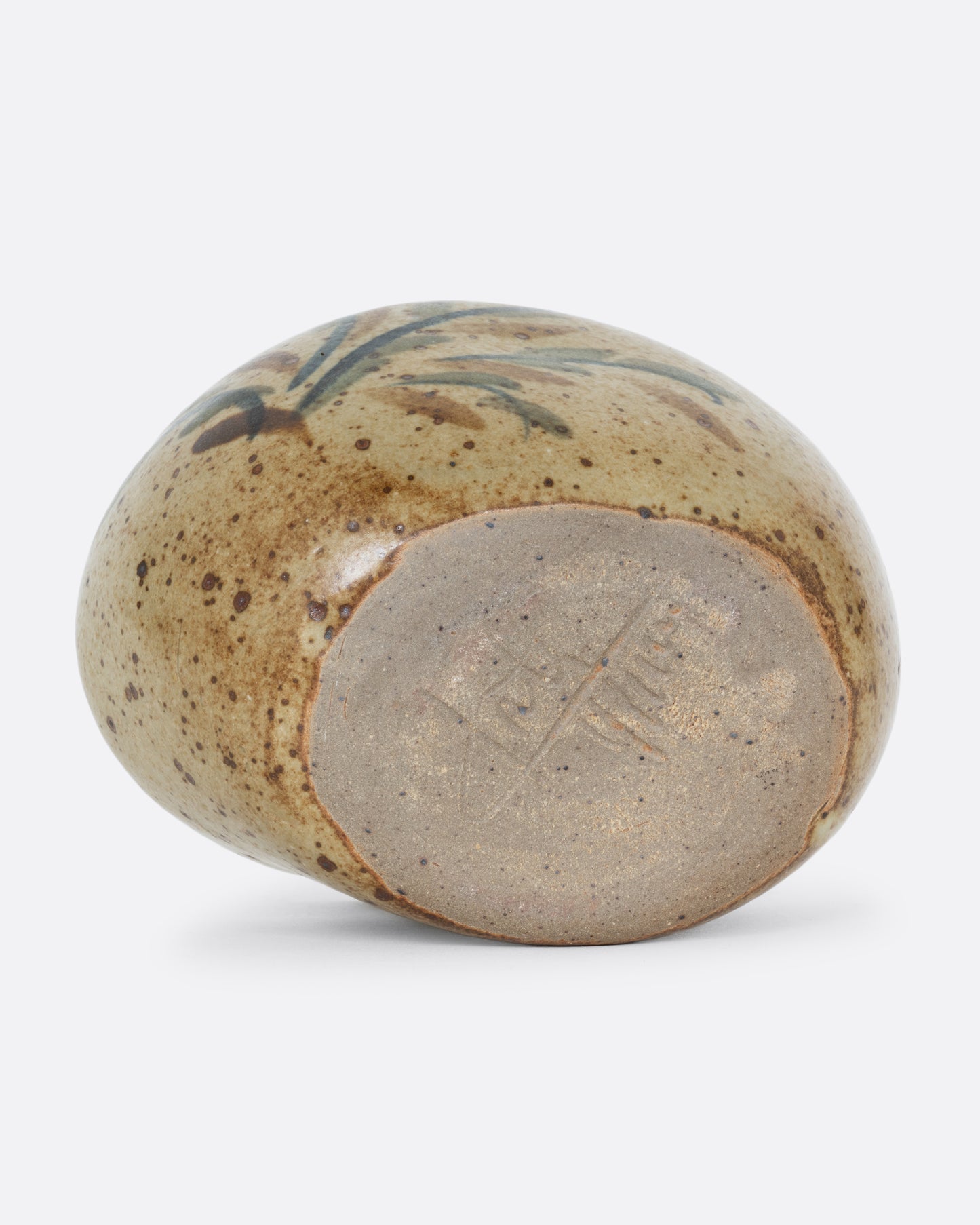 A ceramic bud vase with five small holes for flowers and a cleft at the front with a hand painted floral design. Shown from the bottom.