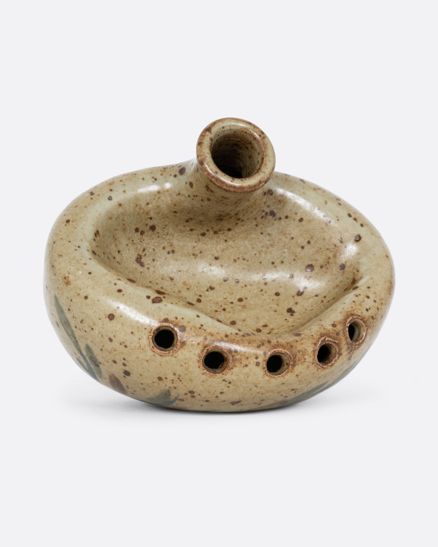A ceramic bud vase with five small holes for flowers and a cleft at the front with a hand painted floral design. Shown lying on its side from the top.