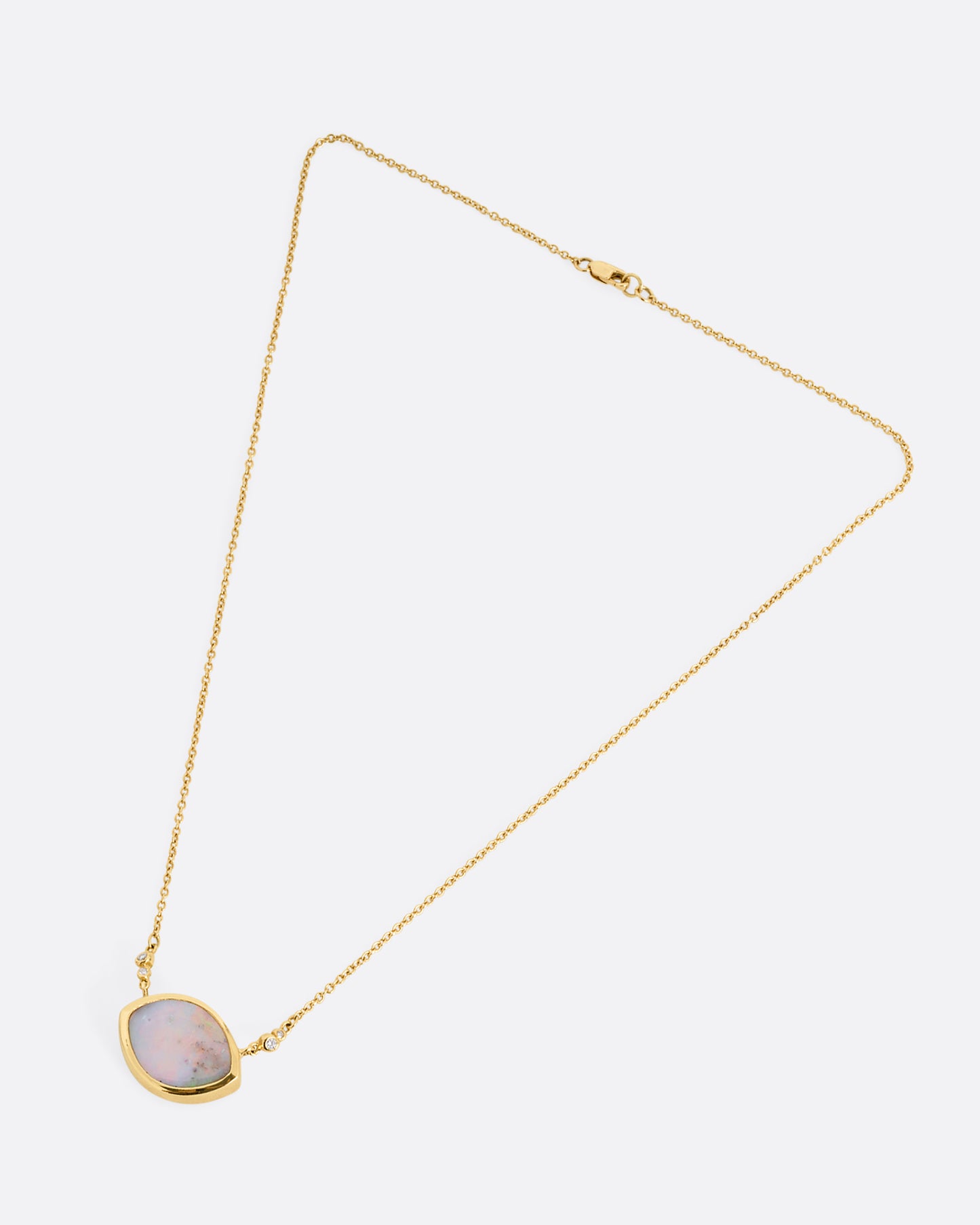 A yellow gold cable chain necklace with a large eye shaped opal pendant and diamond accents. Shown clasped lying flat.
