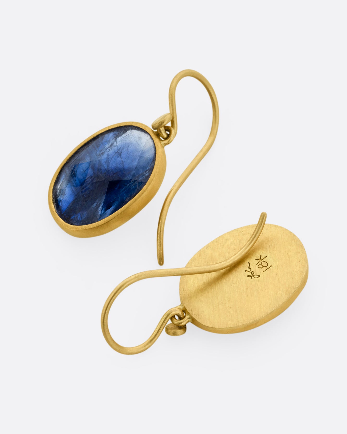 A pair of faceted blue kyanite earrings with yellow gold bezels and ear hooks. One earring is shown from the front, the other from the back.