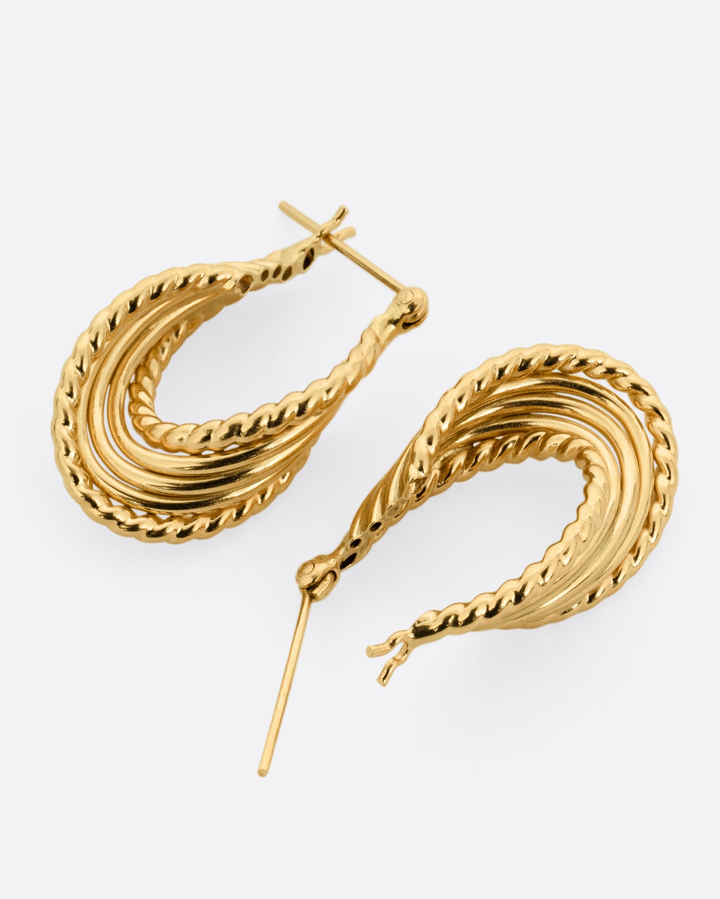 A pair of yellow gold earring with layers of twisted loops and click tops. One earring is shown lying flat from the bottom, the other is shown open lying flat from the top.