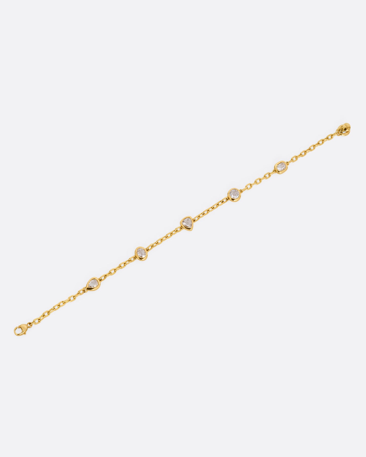 A yellow gold cable chain bracelet with five bezel set diamonds. Shown lying flat open at an angle.