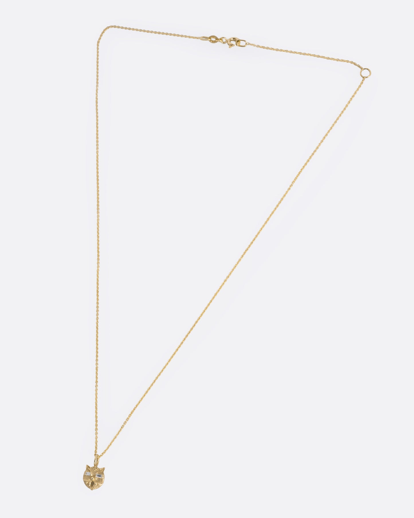 A yellow gold cable chain necklace with a cat head shaped pendant with baguette diamond eyes, shown from the front.
