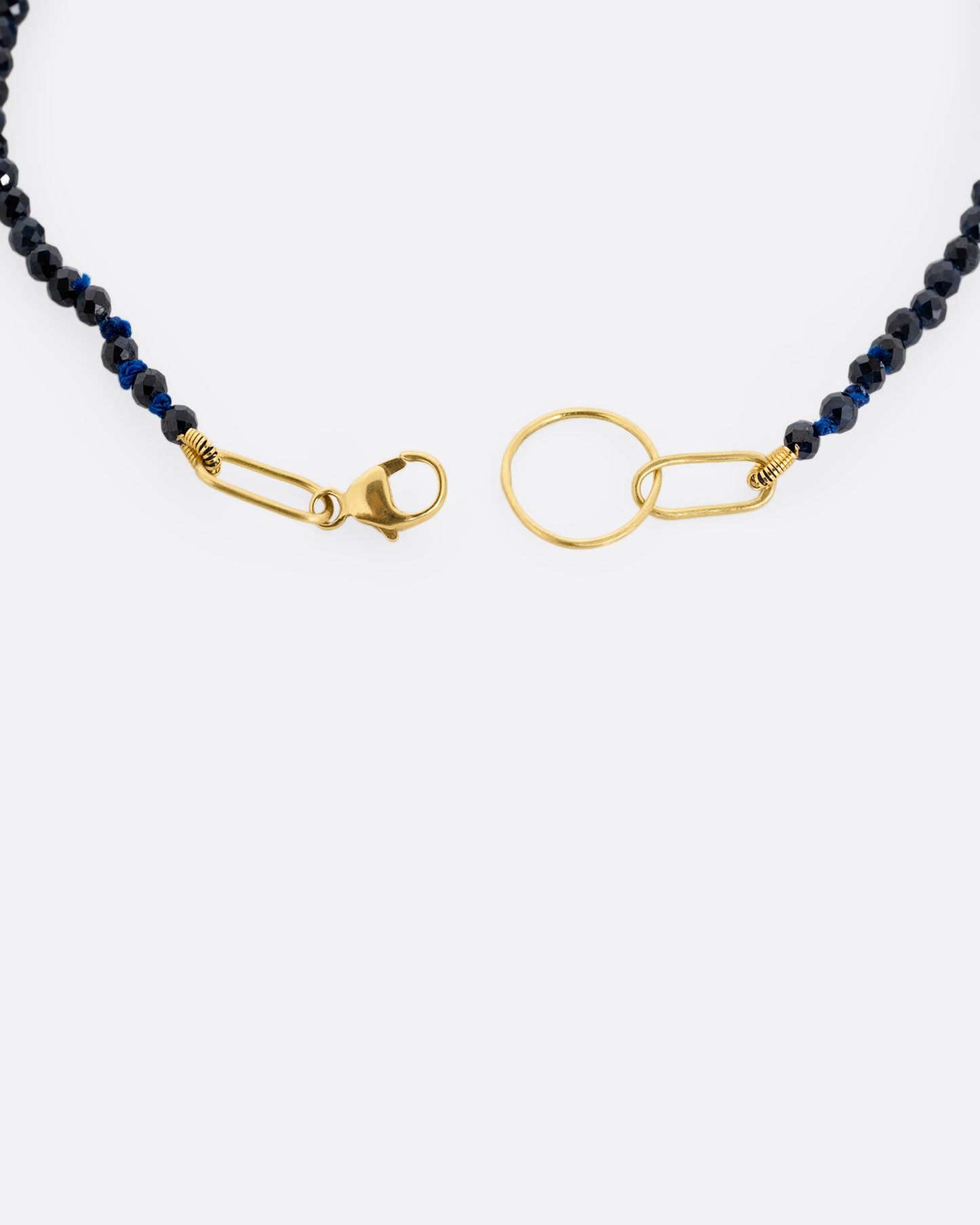 A close up of a beaded ruby bracelet with a yellow gold clasp.
