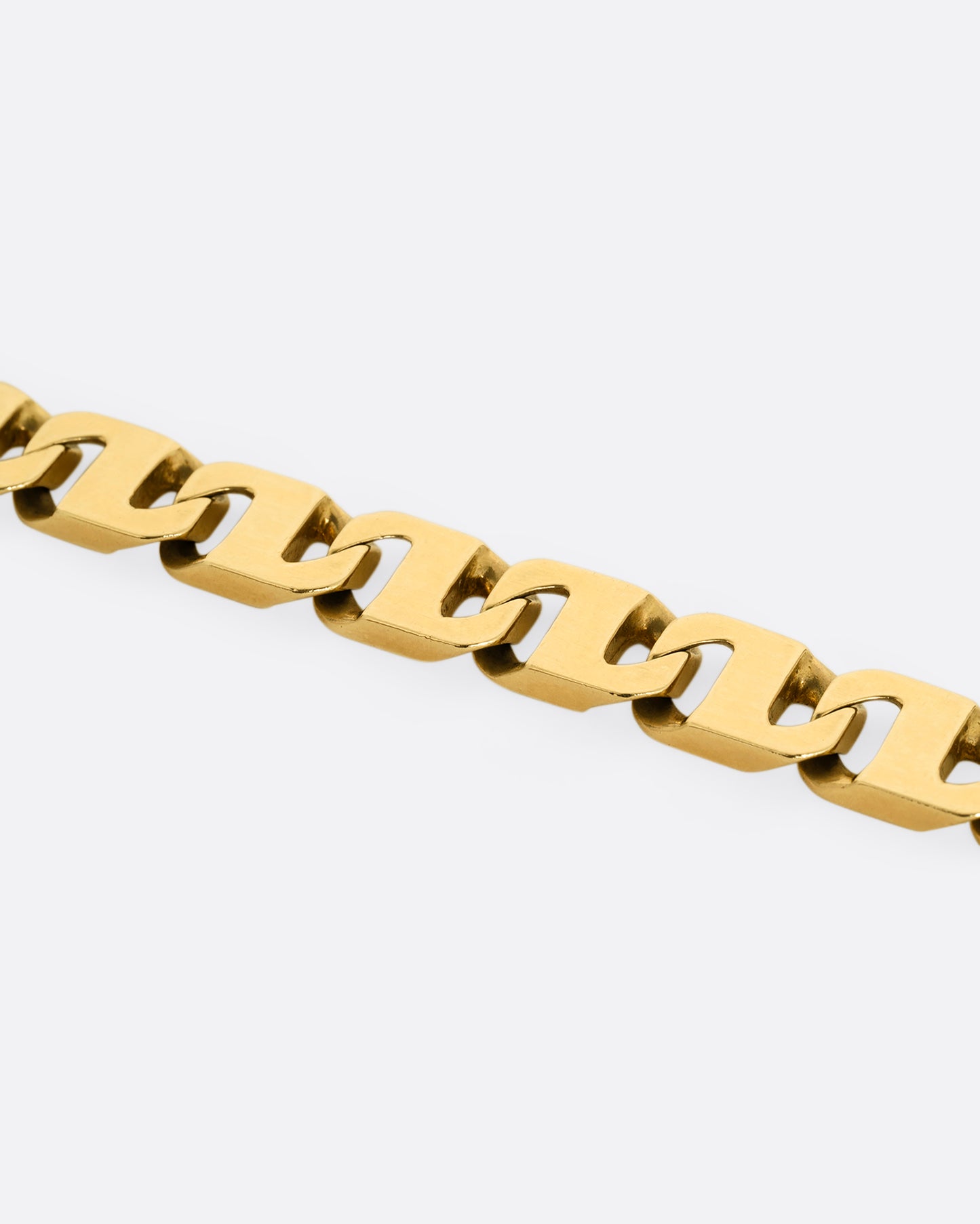 A close up of yellow gold anchor link bracelet. Shown lying flat from the front.