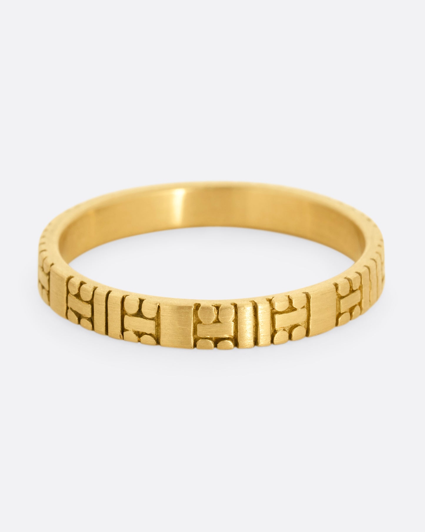 A yellow gold band with dots and dashes in a symmetrical pattern. Shown from the front.