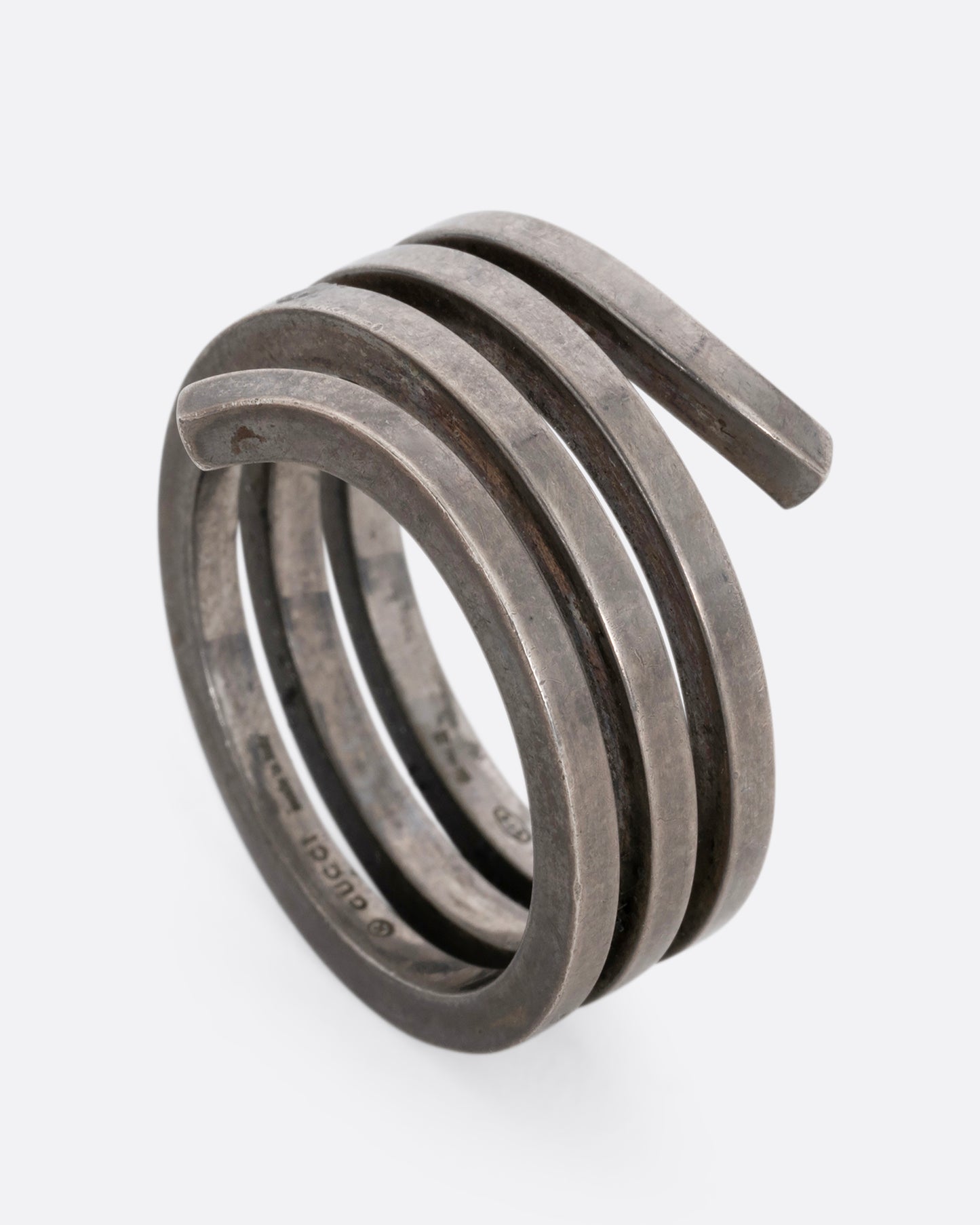 A silver ring with a coil silhouette. Shown standing up from the side.