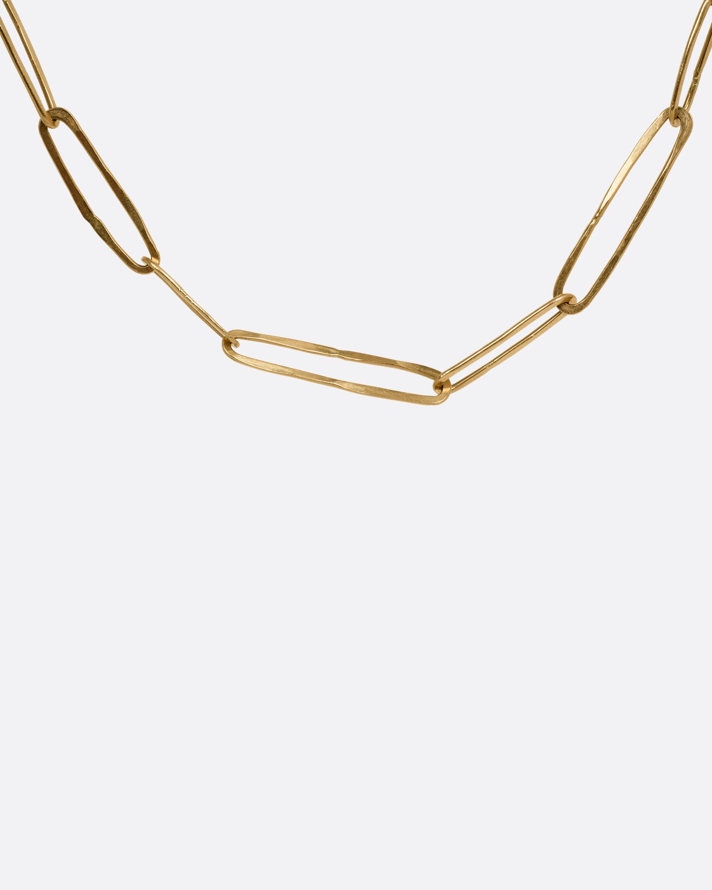 A close up of a yellow gold paperclip chain shown from the front.