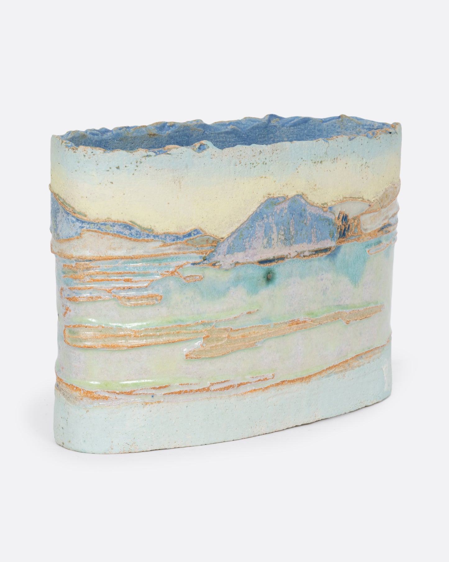 An oblong ceramic vessel with a landscape on it. Shown at an angle from the front.