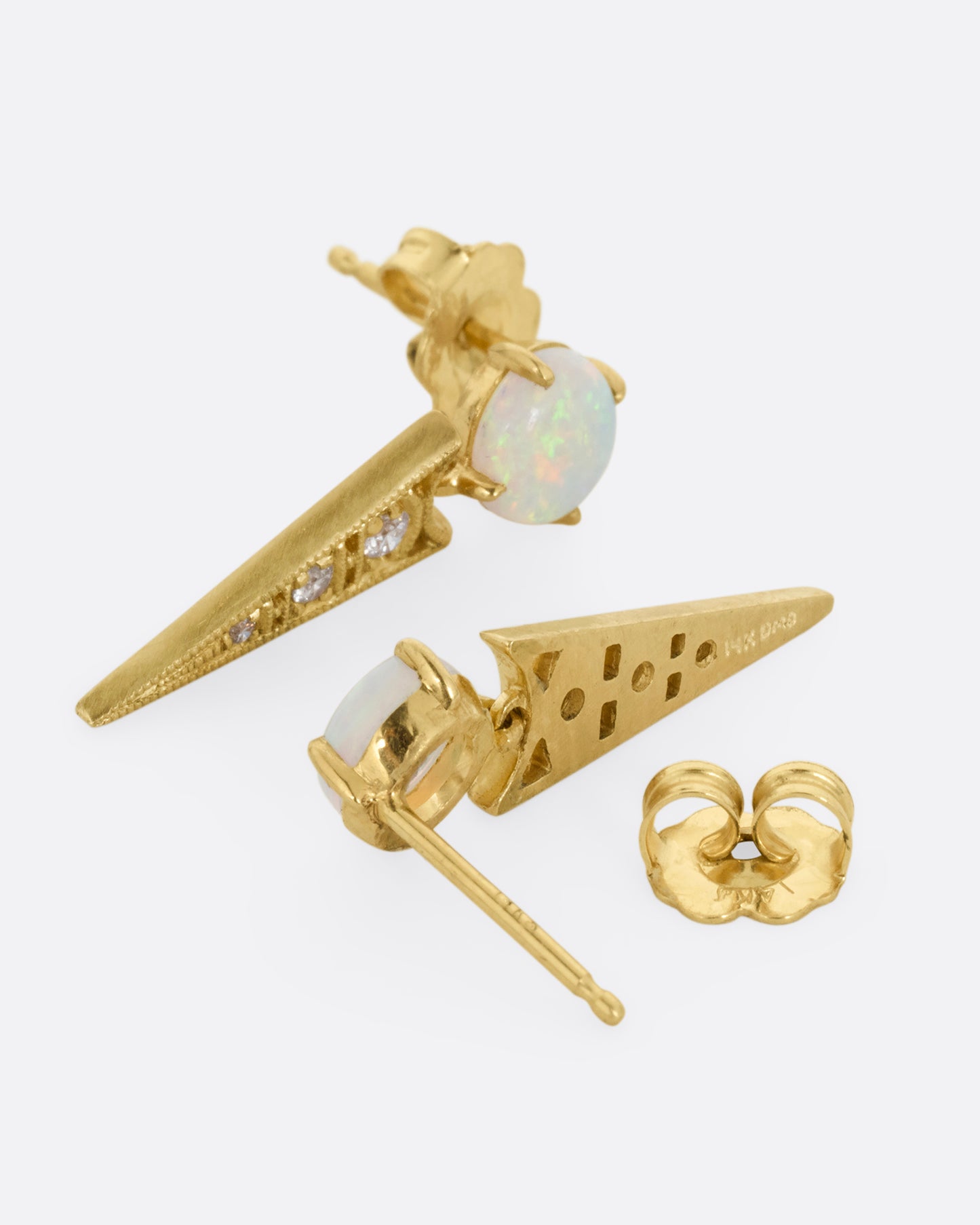 A pair of yellow gold earrings with prong set Australian opals and pointed drops with cutouts and a trio of diamonds. Shown lying on their sides; one from the front the other from the back, open.