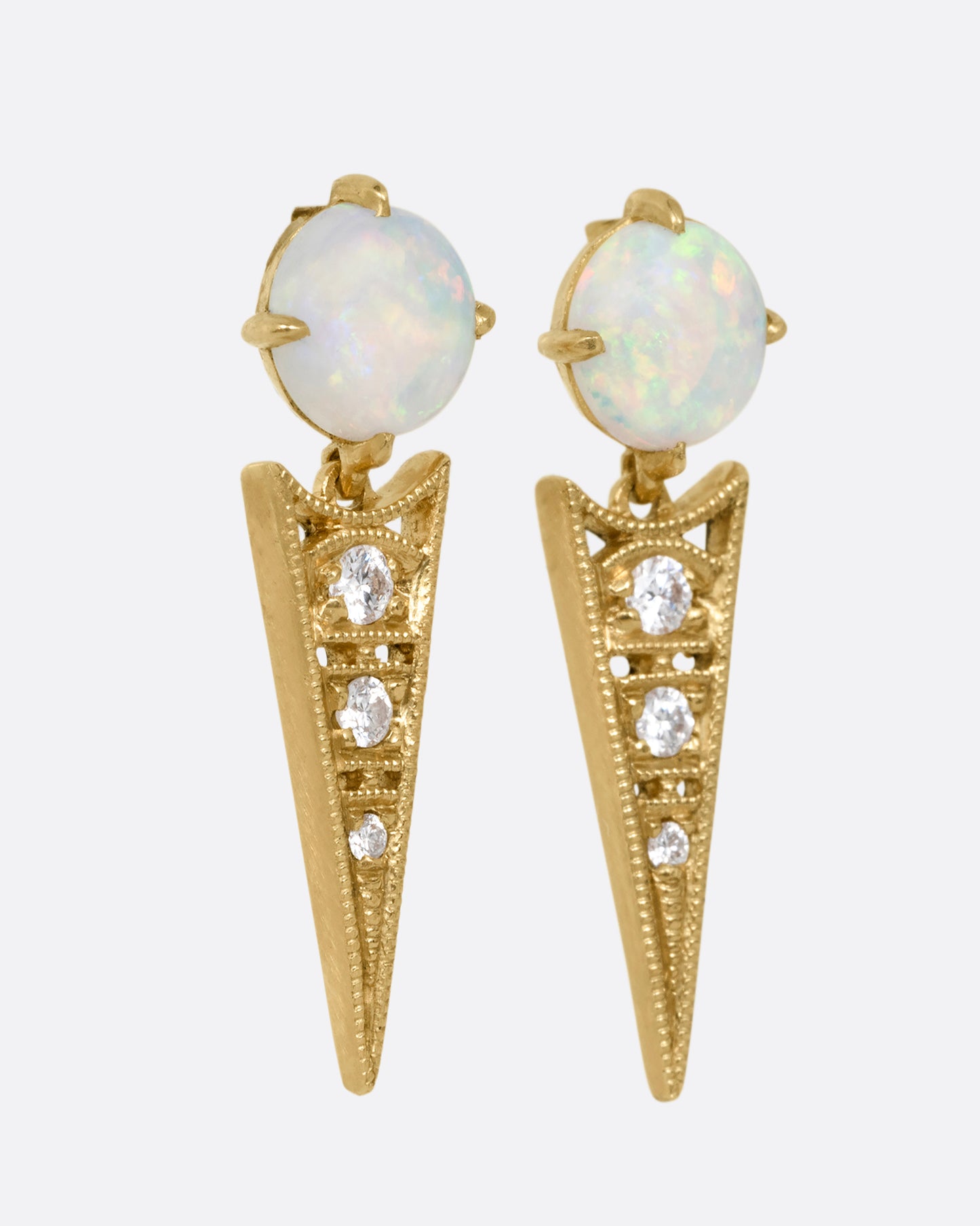 A pair of yellow gold earrings with prong set Australian opals and pointed drops with cutouts and a trio of diamonds. Shown from the side.