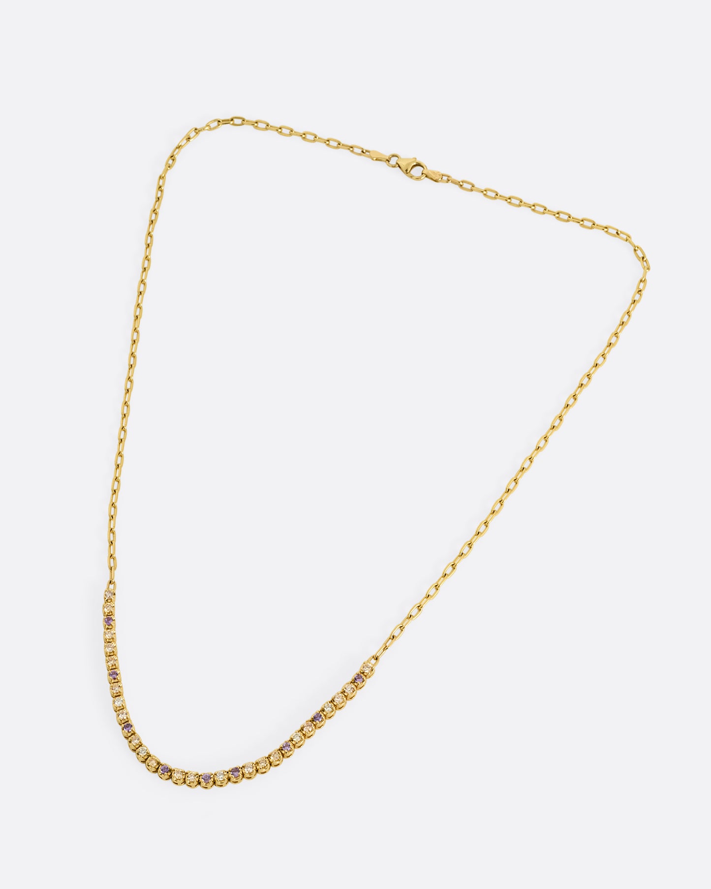 A yellow gold cable chain necklace with peach and yellow diamonds and purple sapphires in a 'partial tennis' setting. Shown closed lying flat from the front.