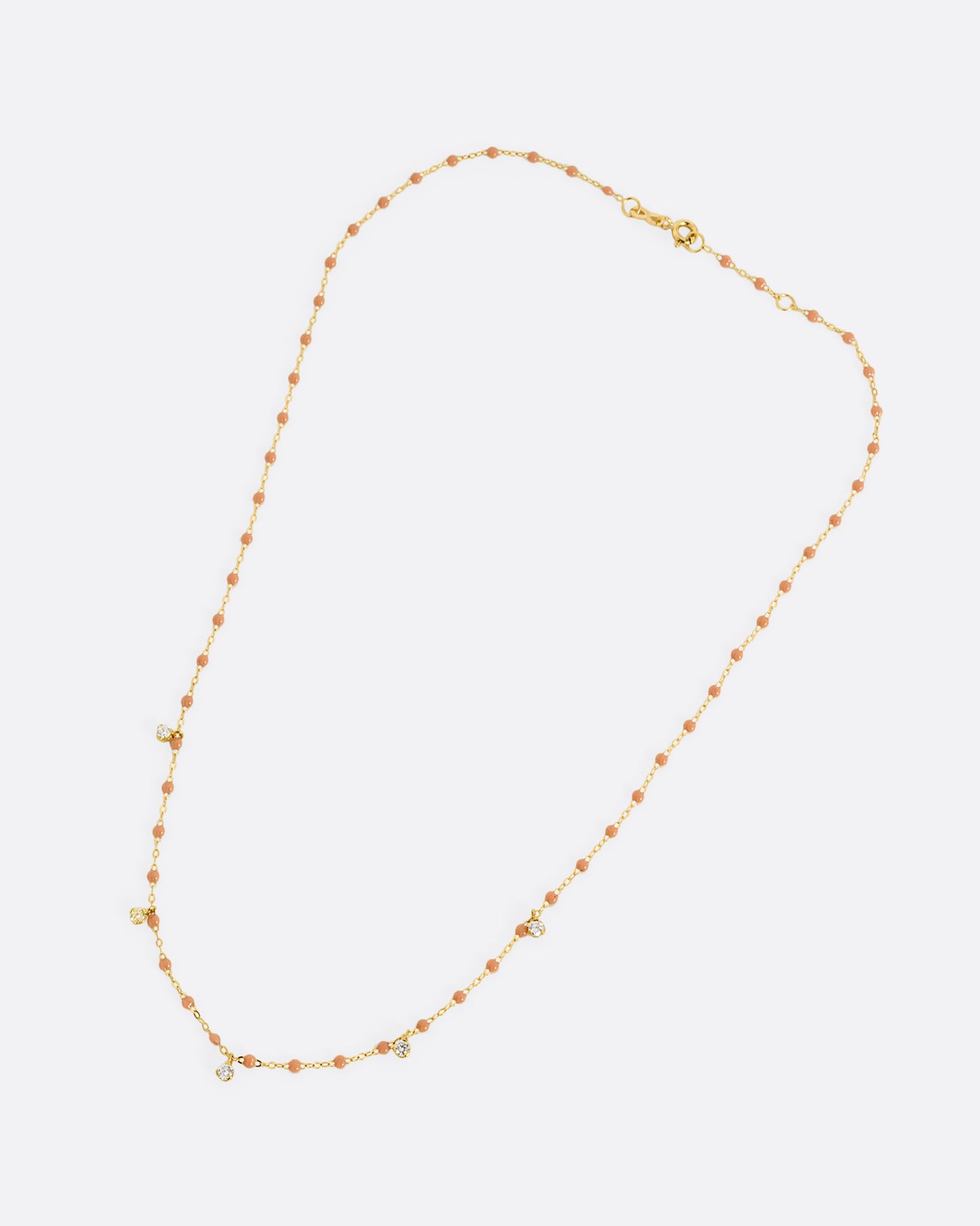 A yellow gold cable chain necklace with caramel brown resin droplets along the chain and five dangling diamond charms. Shown closed lying flat from the front.