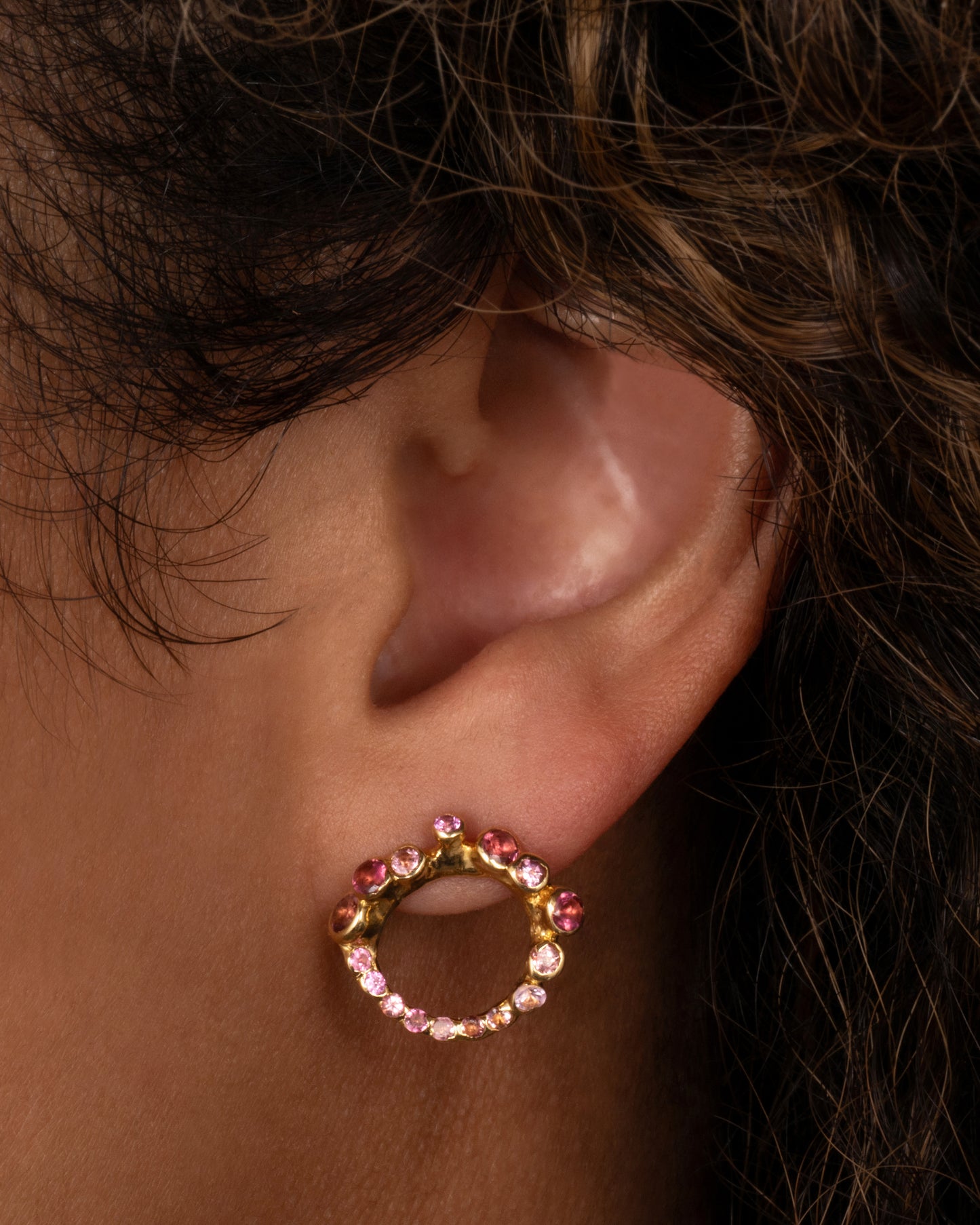 yellow gold earrings with pink and red tourmalines shown on an ear