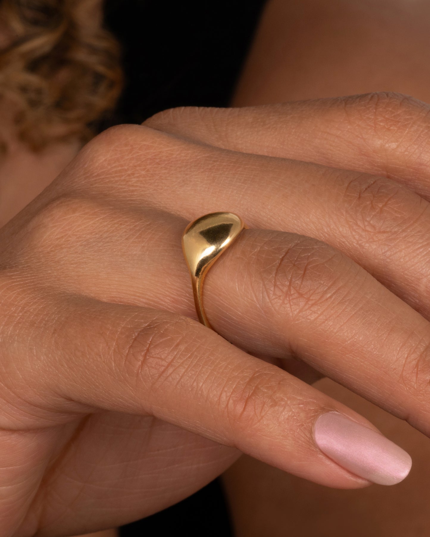 A yellow gold rounded signet ring. Shown worn on a finger.