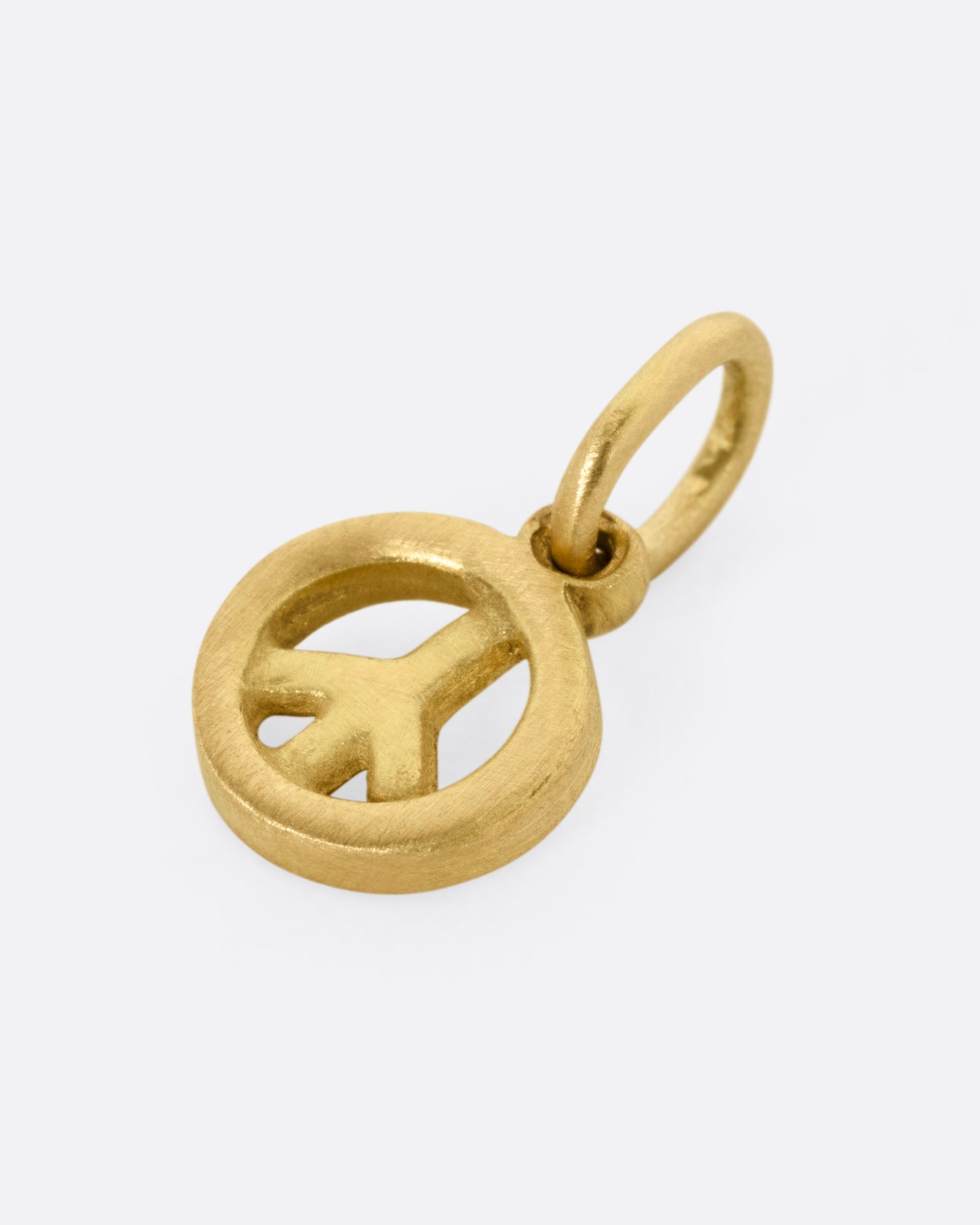 A yellow gold peace sign pendant shown from the side.