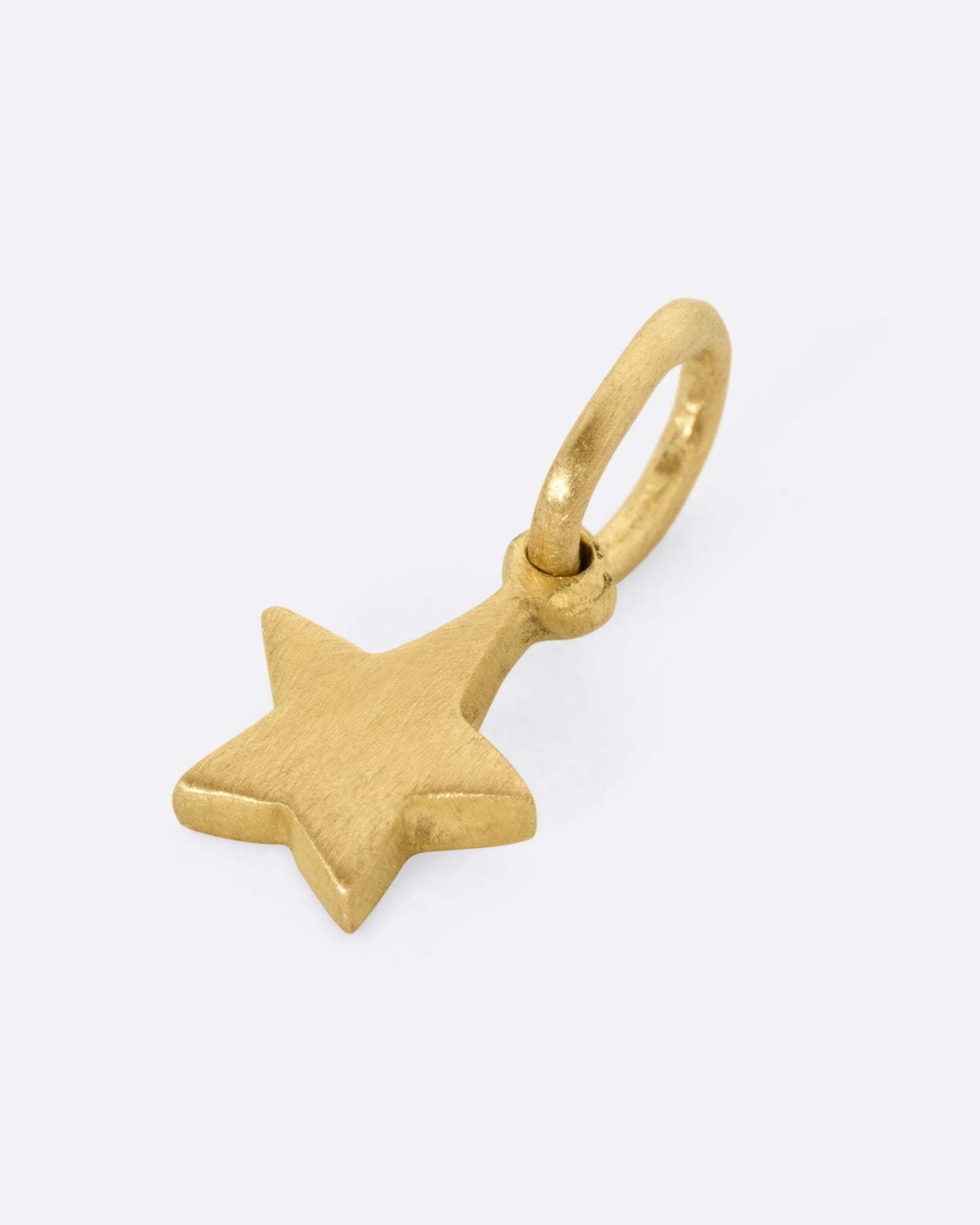 A yellow gold star shaped pendant shown from the side.