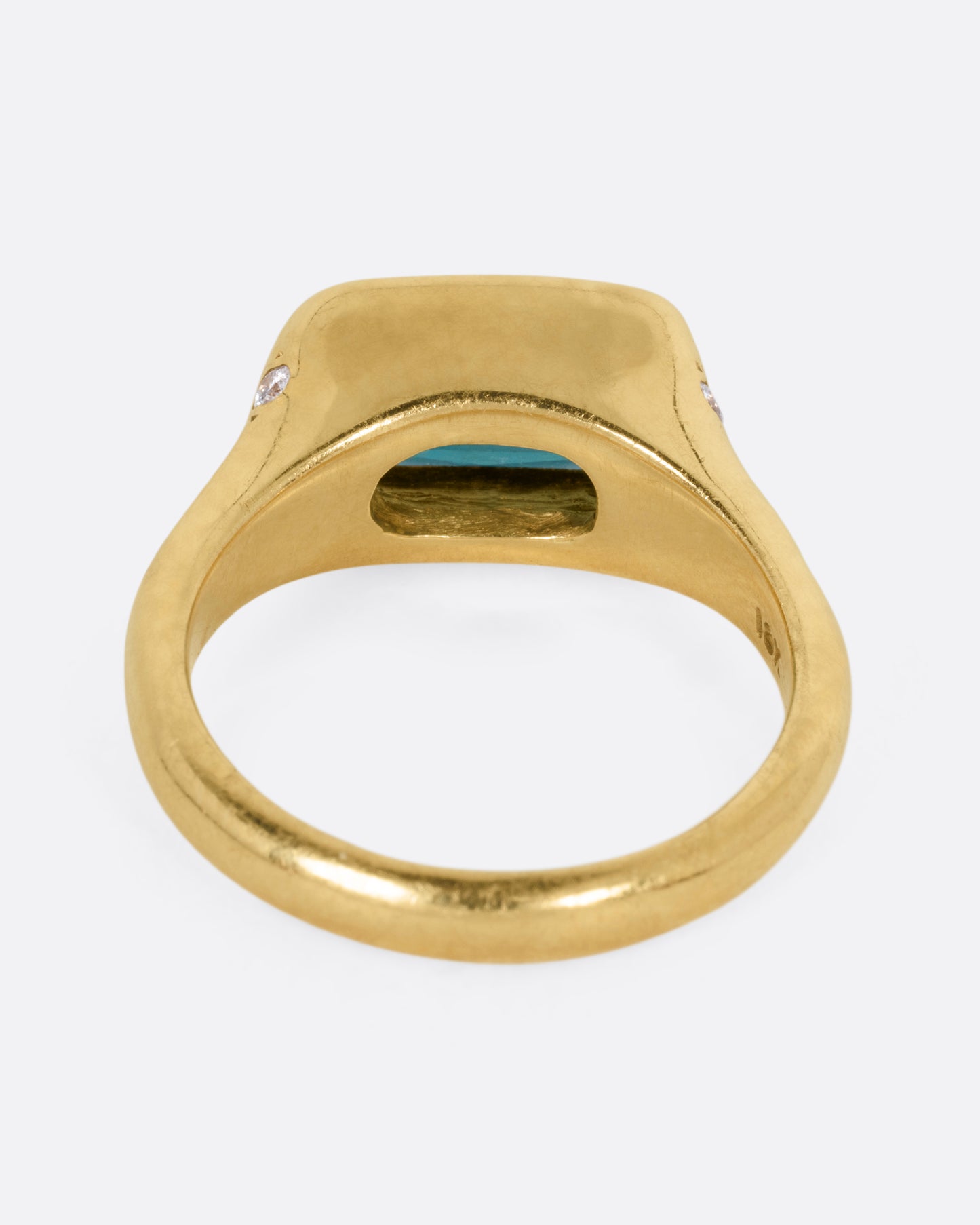 A yellow gold ring with a rectangular green tourmaline at the center and diamonds on either shoulder. Shown from the back.