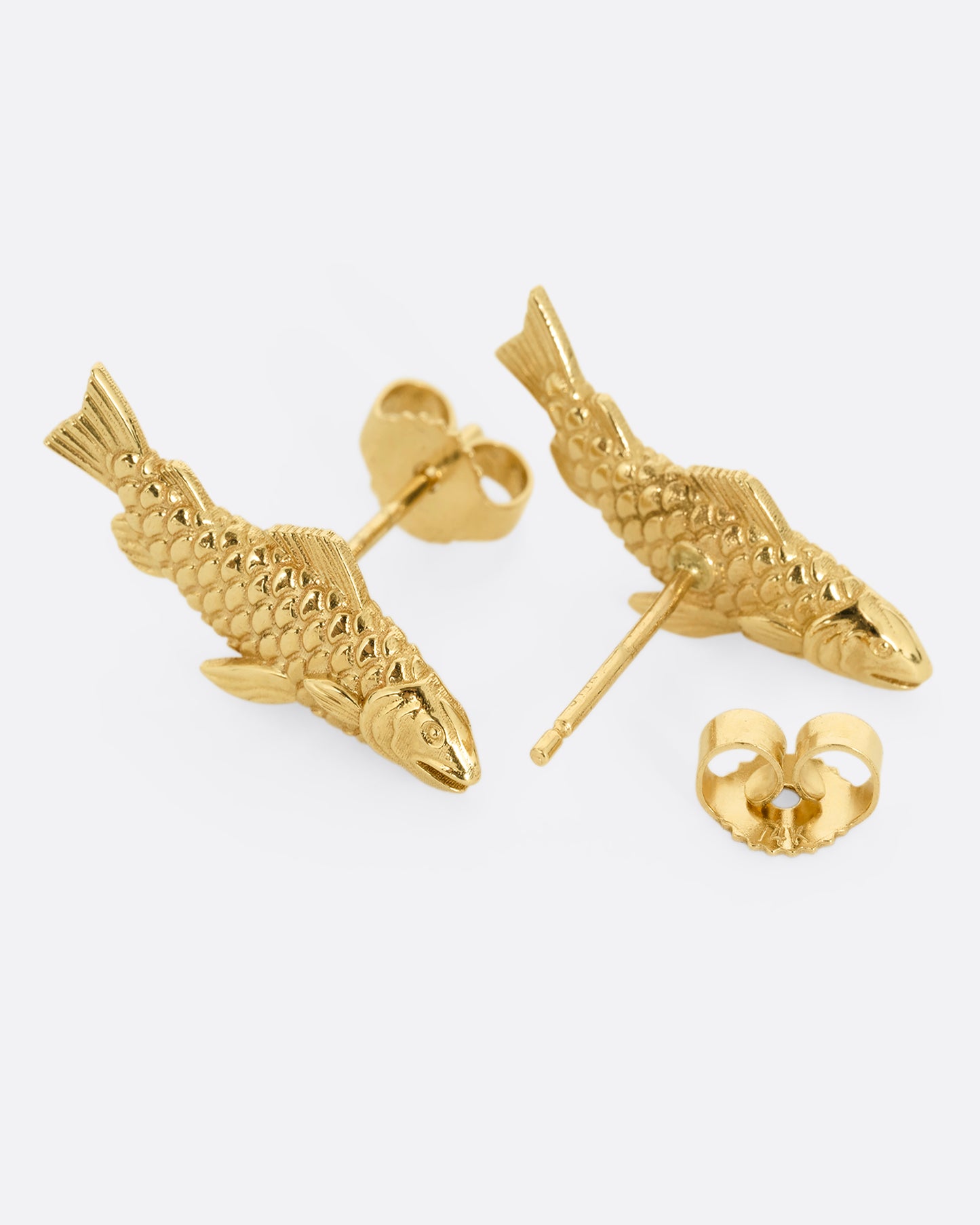 A pair of yellow gold fish earrings. Shown on their sides; one from the front, the other open from the back.
