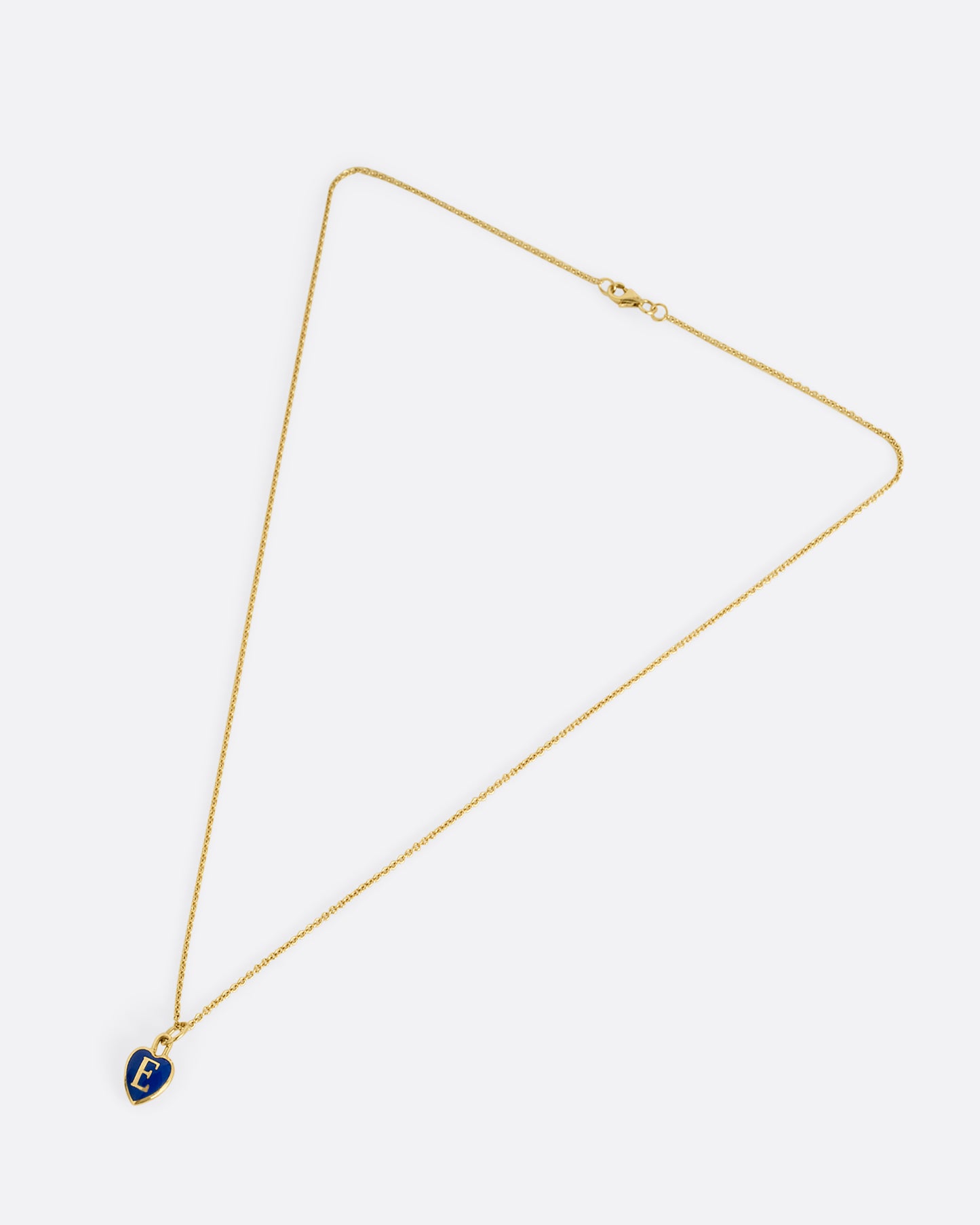 A yellow gold cable chain necklace with a blue enamel heart with a letter E at its center. Shown closed lying flat at an angle from the front.