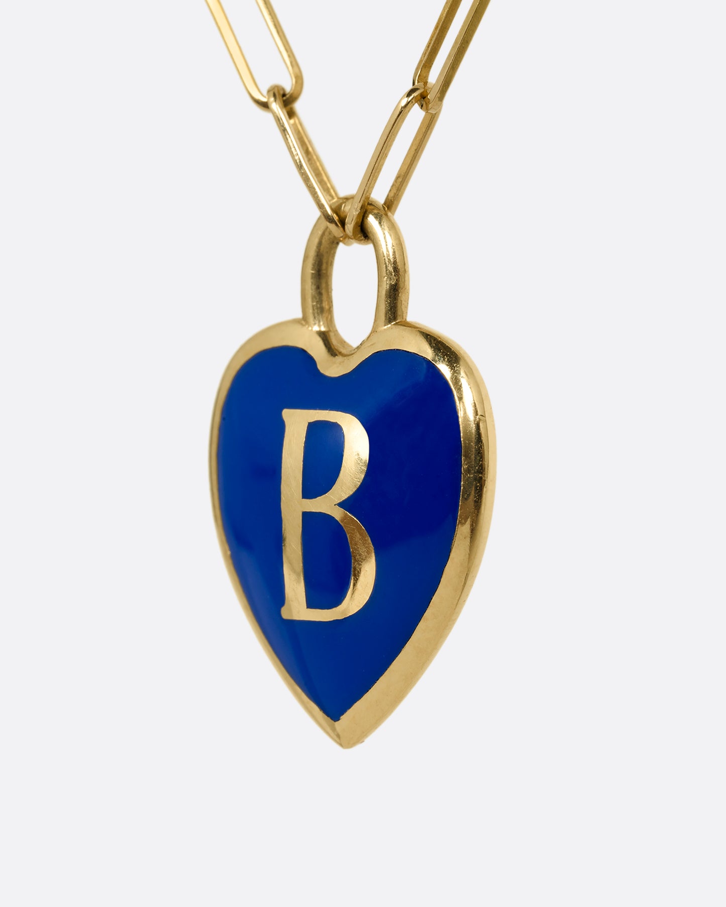 A yellow gold paperclip chain necklace with a black enamel heart shaped N pendant. Shown from the side.