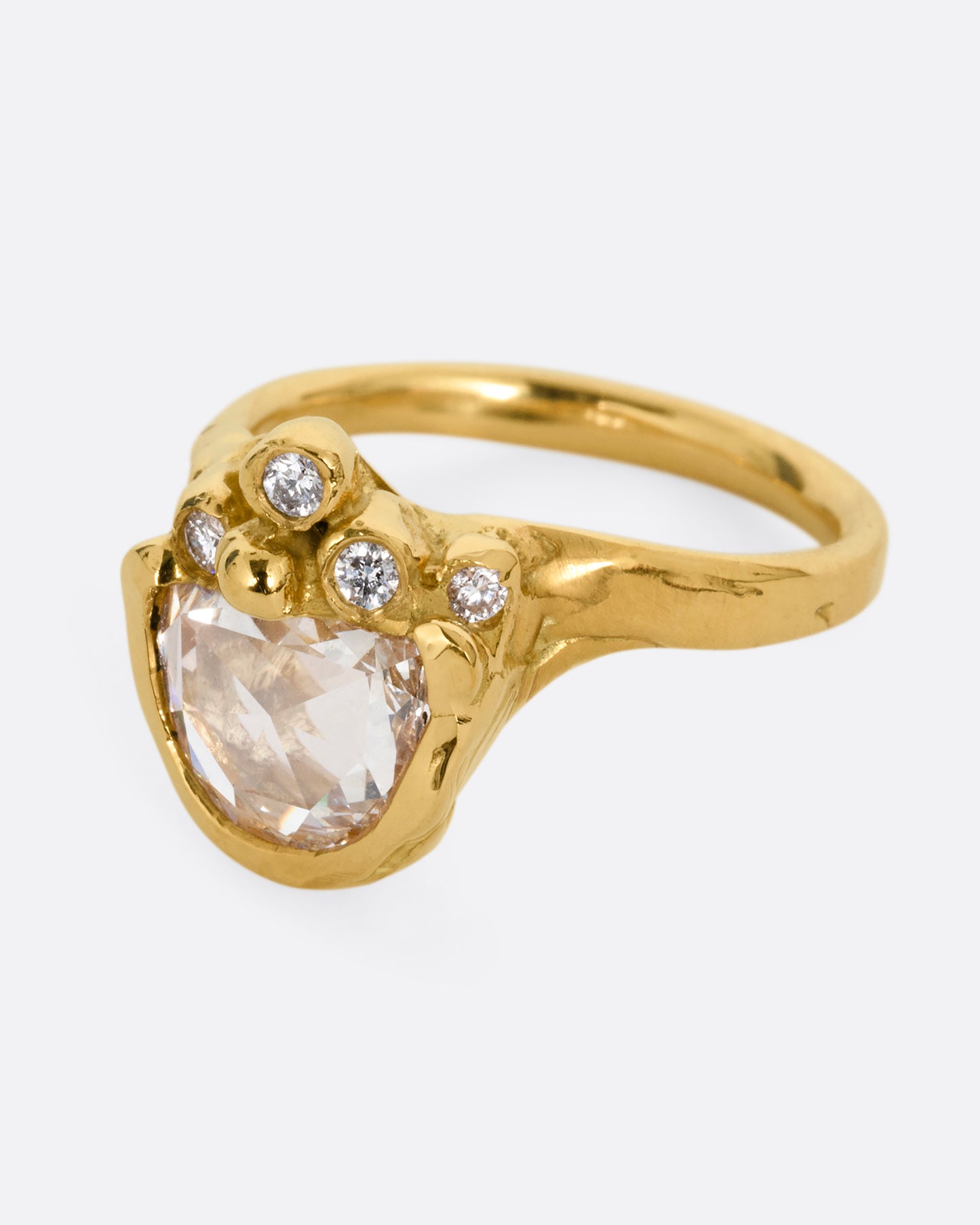 A yellow gold ring with a central rose cut diamond half moon and bezel set diamond accents on top of the flat side. Shown from the side.