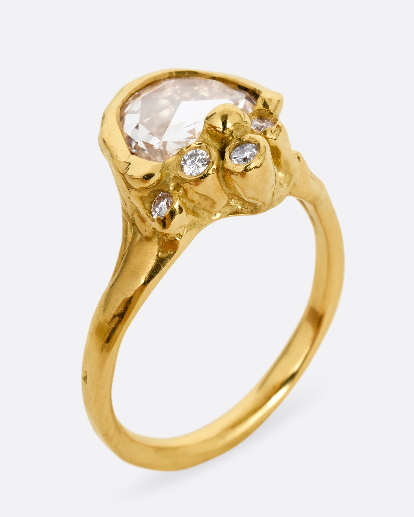 A yellow gold ring with a central rose cut diamond half moon and bezel set diamond accents on top of the flat side. Shown from the side at an angle.