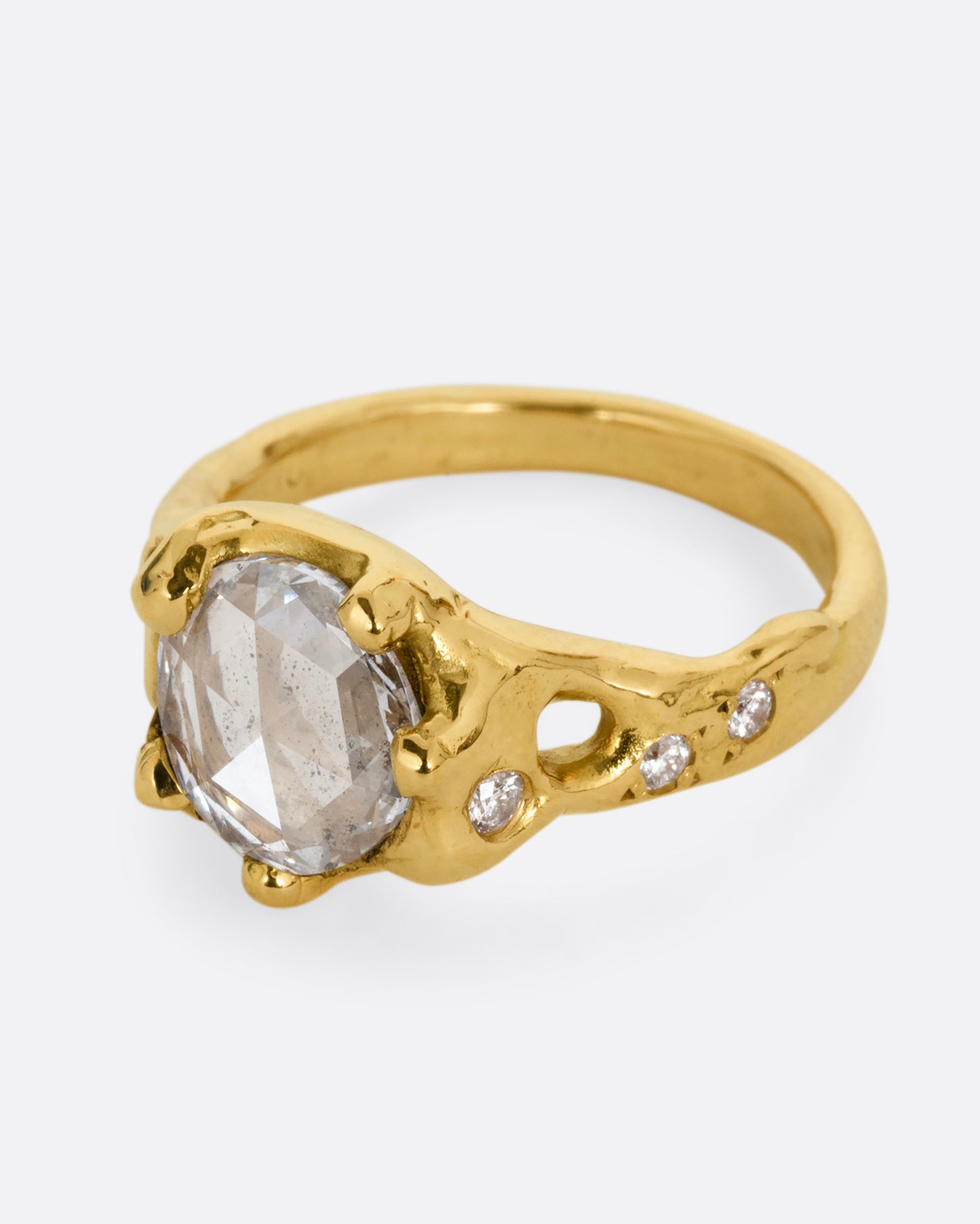 A yellow gold ring with a rose cut diamond, cutouts, and diamond details. Shown from the side.