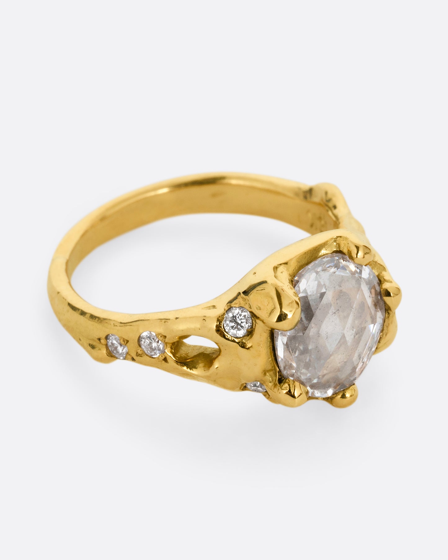 A yellow gold ring with a rose cut diamond, cutouts, and diamond details. Shown from the side.