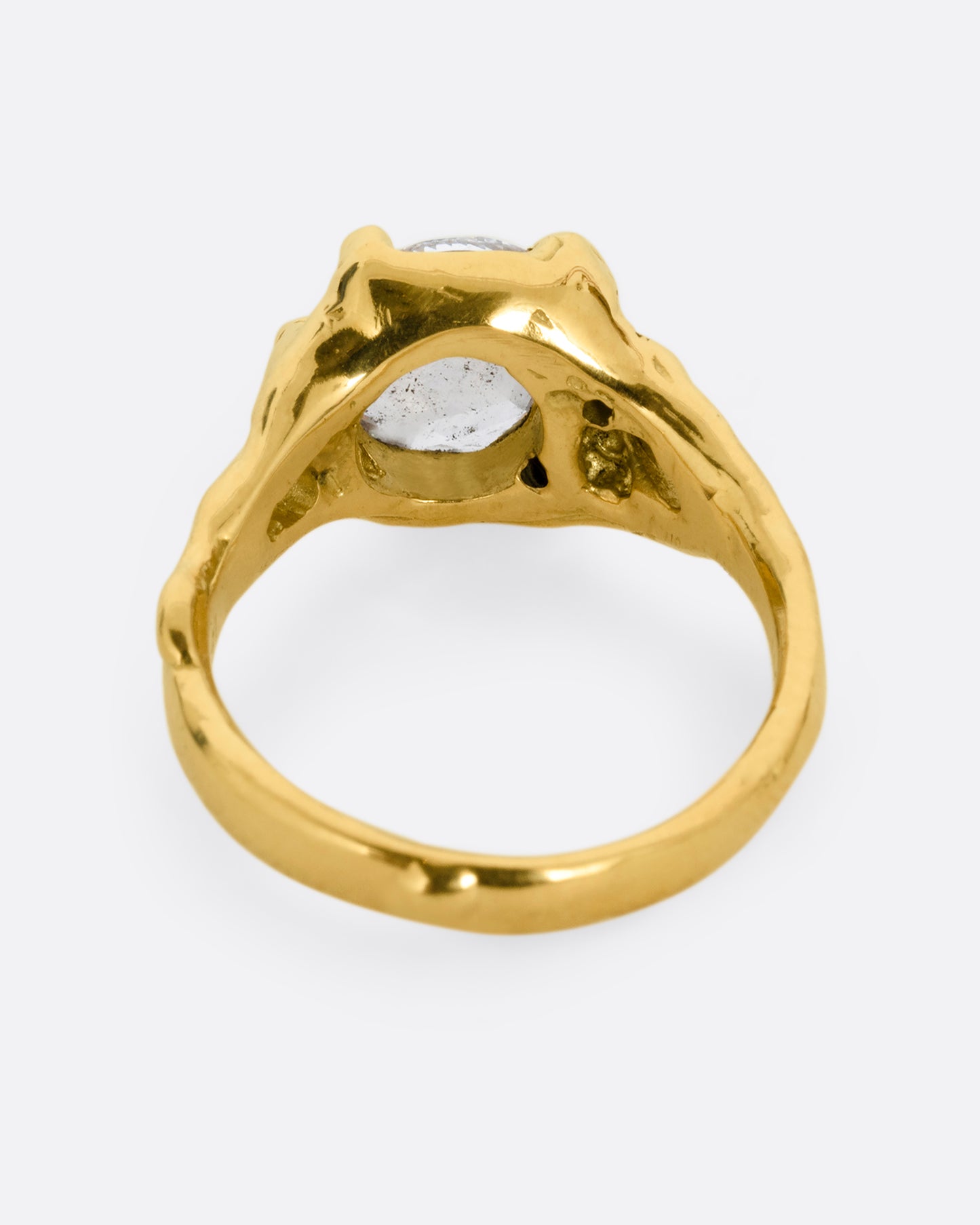 A yellow gold ring with a rose cut diamond, cutouts, and diamond details. Shown from the back.