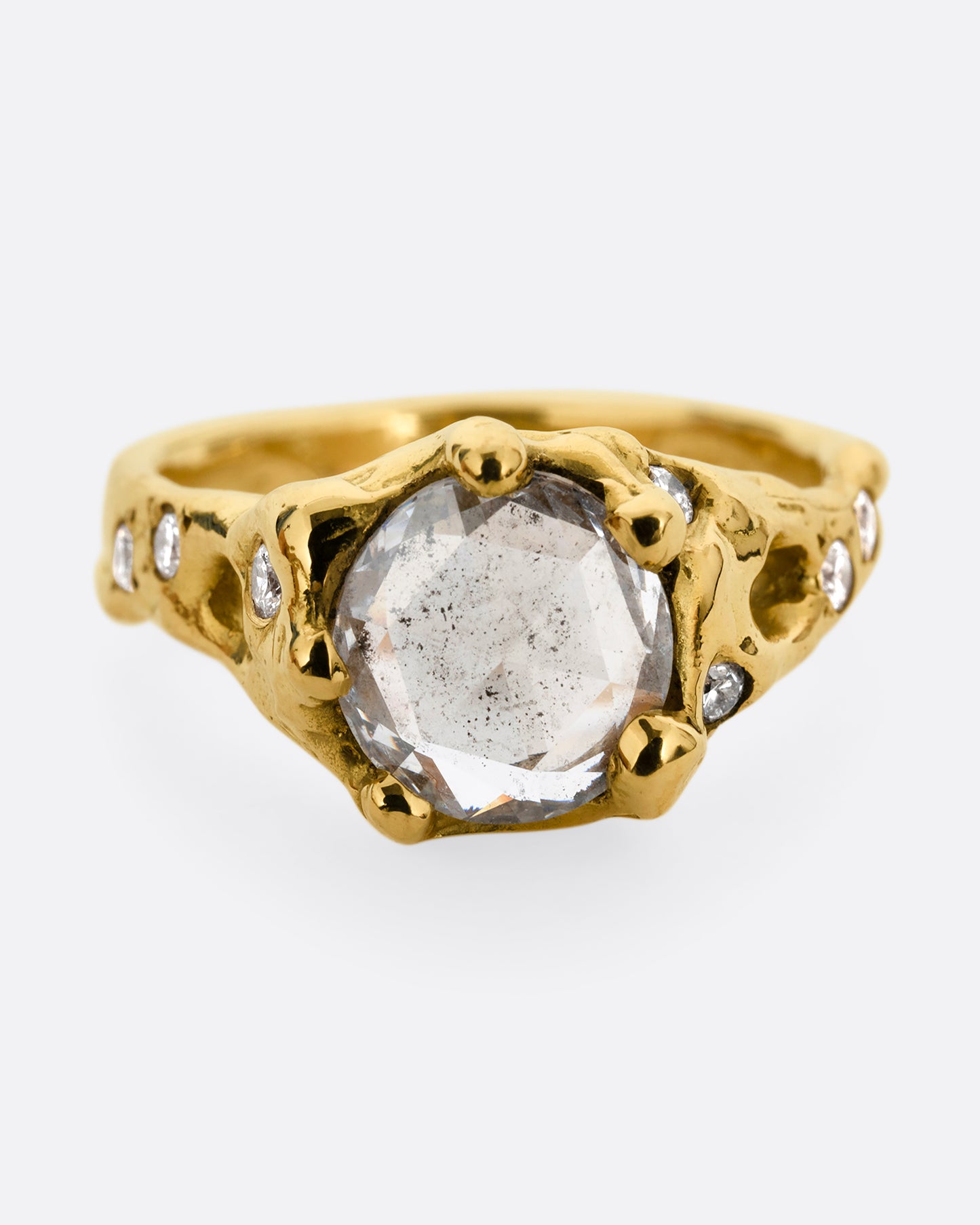 A yellow gold ring with a rose cut diamond, cutouts, and diamond details. Shown from the front.