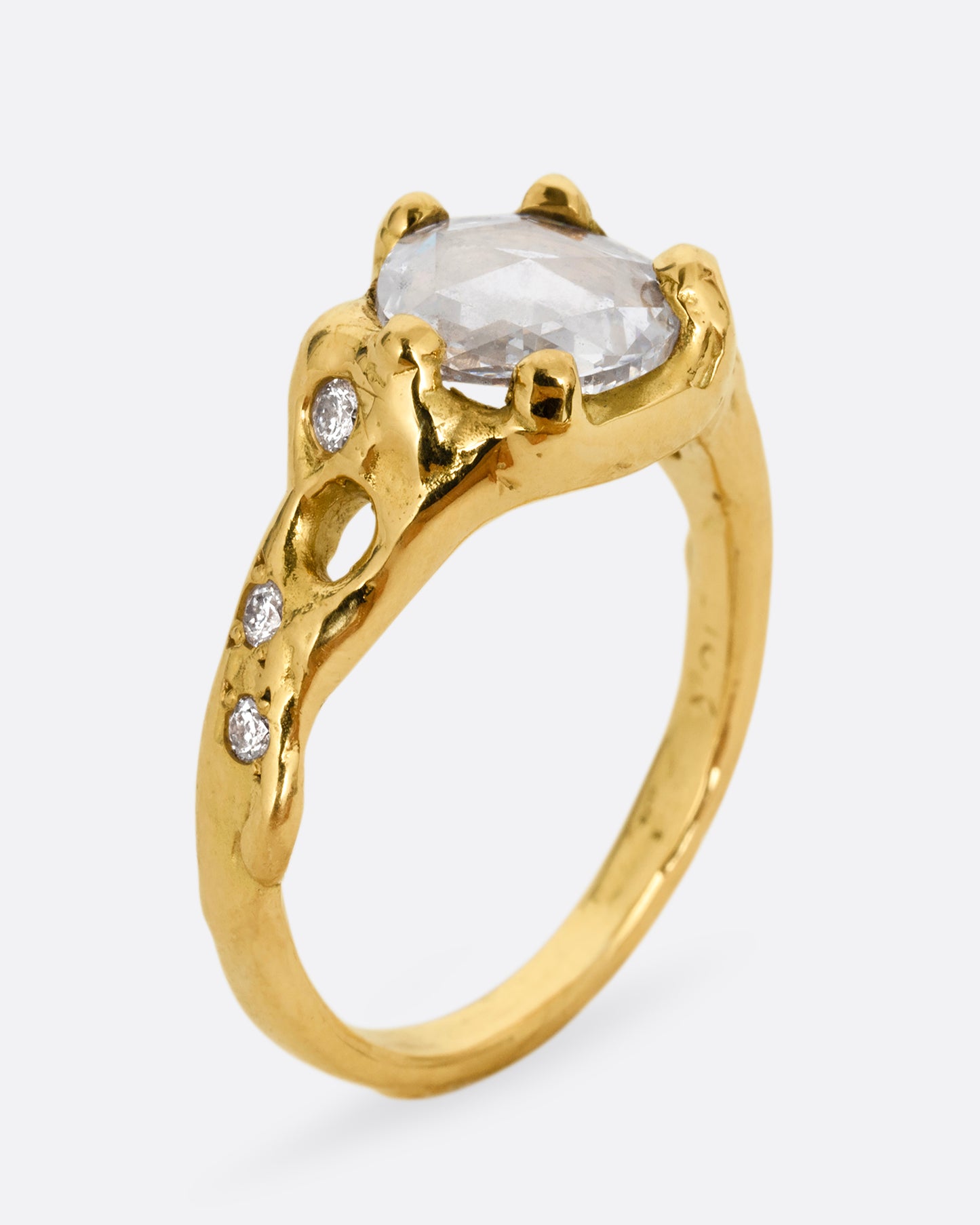 A yellow gold ring with a rose cut diamond, cutouts, and diamond details. Shown standing up from the side.