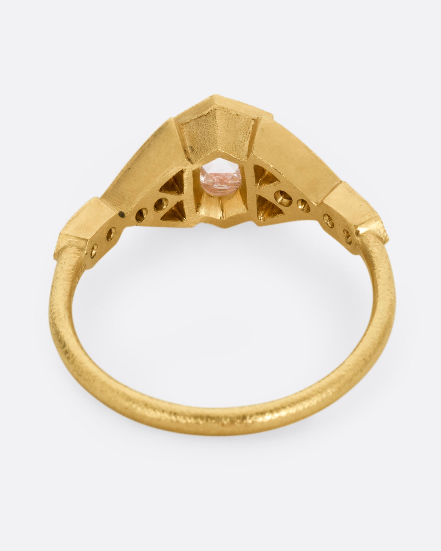 A yellow gold ring with a center diamond and angular side cutouts and diamond accents. Shown from the back.