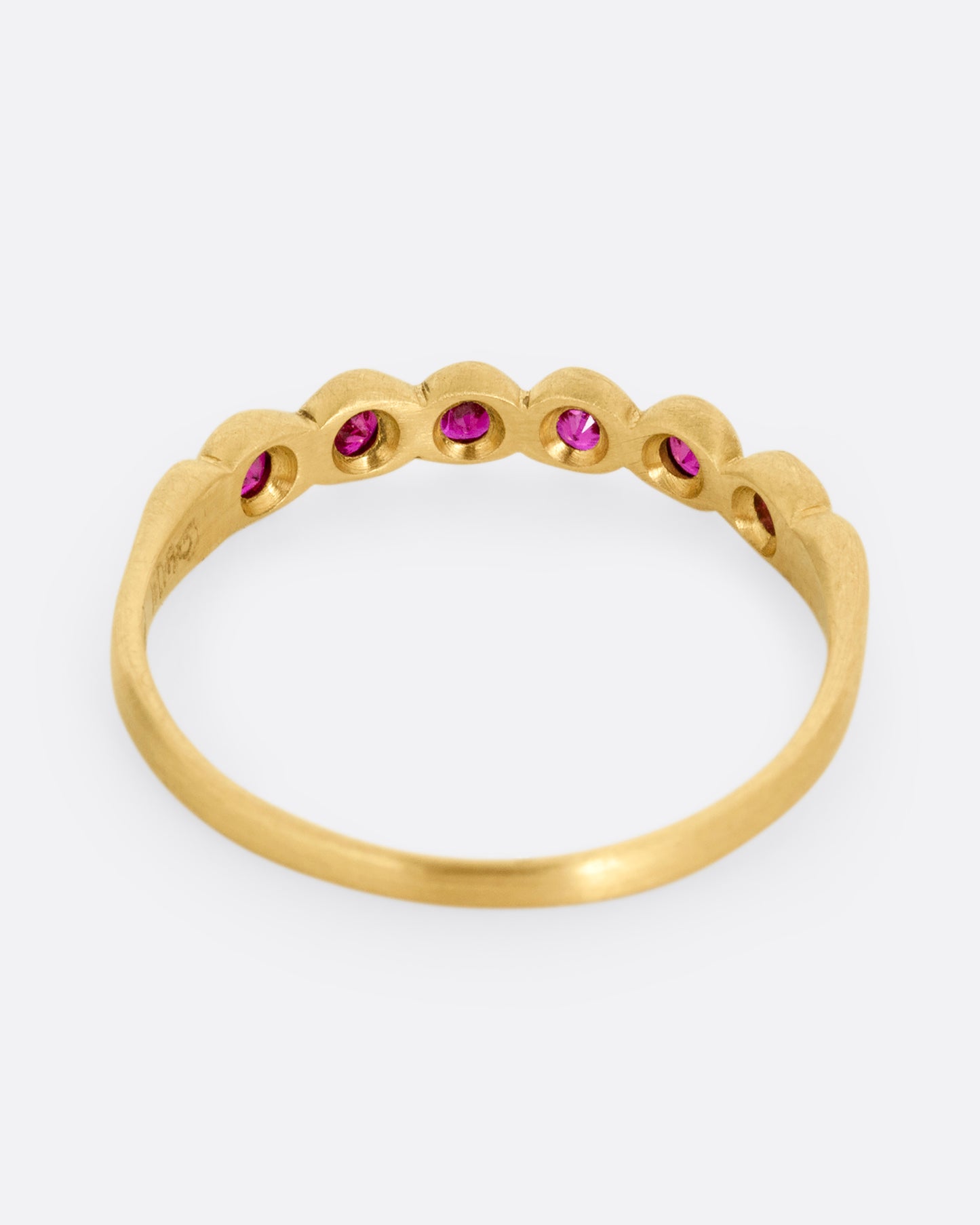 A yellow gold ring with six bezel set rubies. Shown from the back.