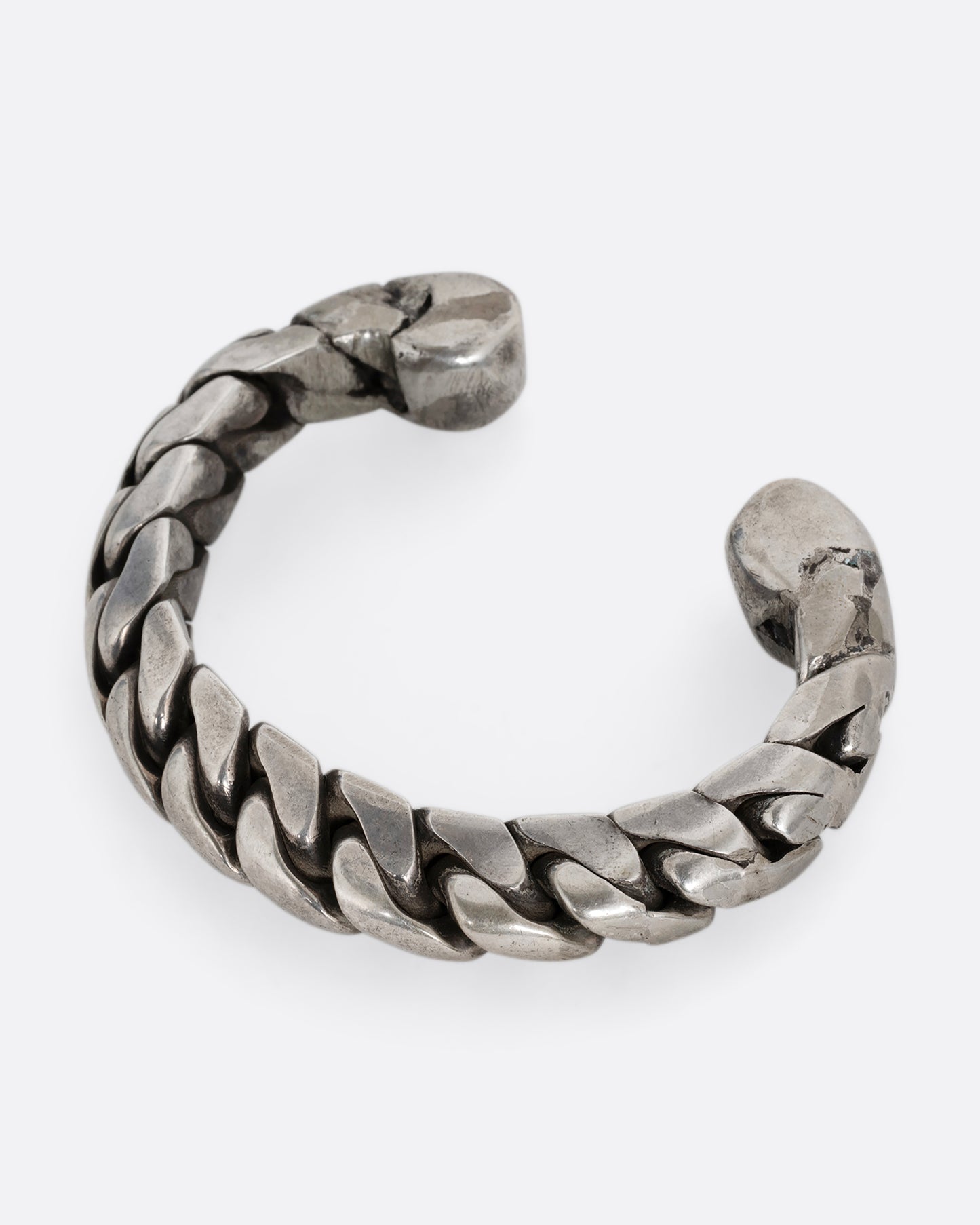 A silver curb chain cuff bracelet, soldered stiff with an open back. Shown from the side.