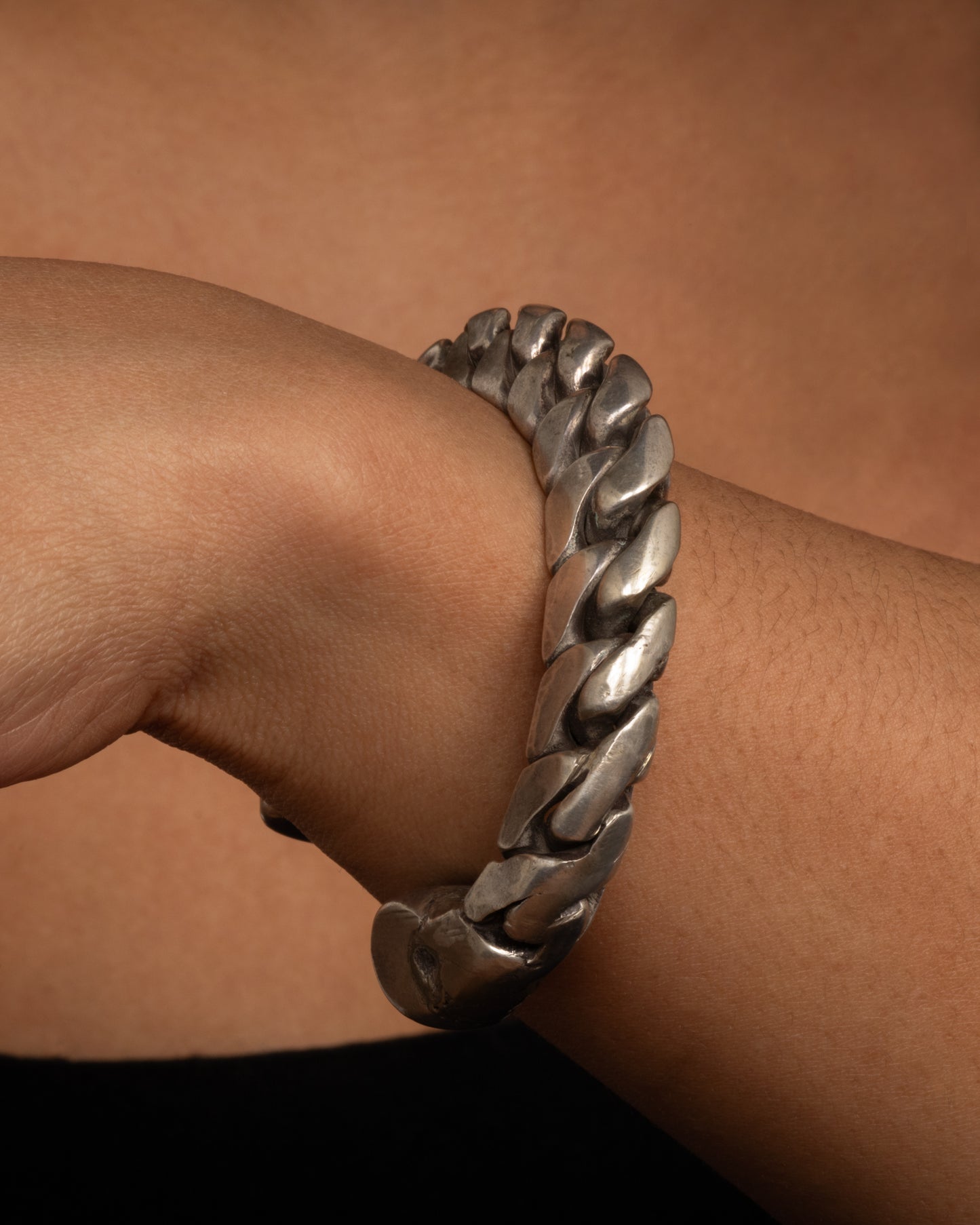 A silver curb chain cuff bracelet, soldered stiff with an open back. Shown from the side on a wrist.