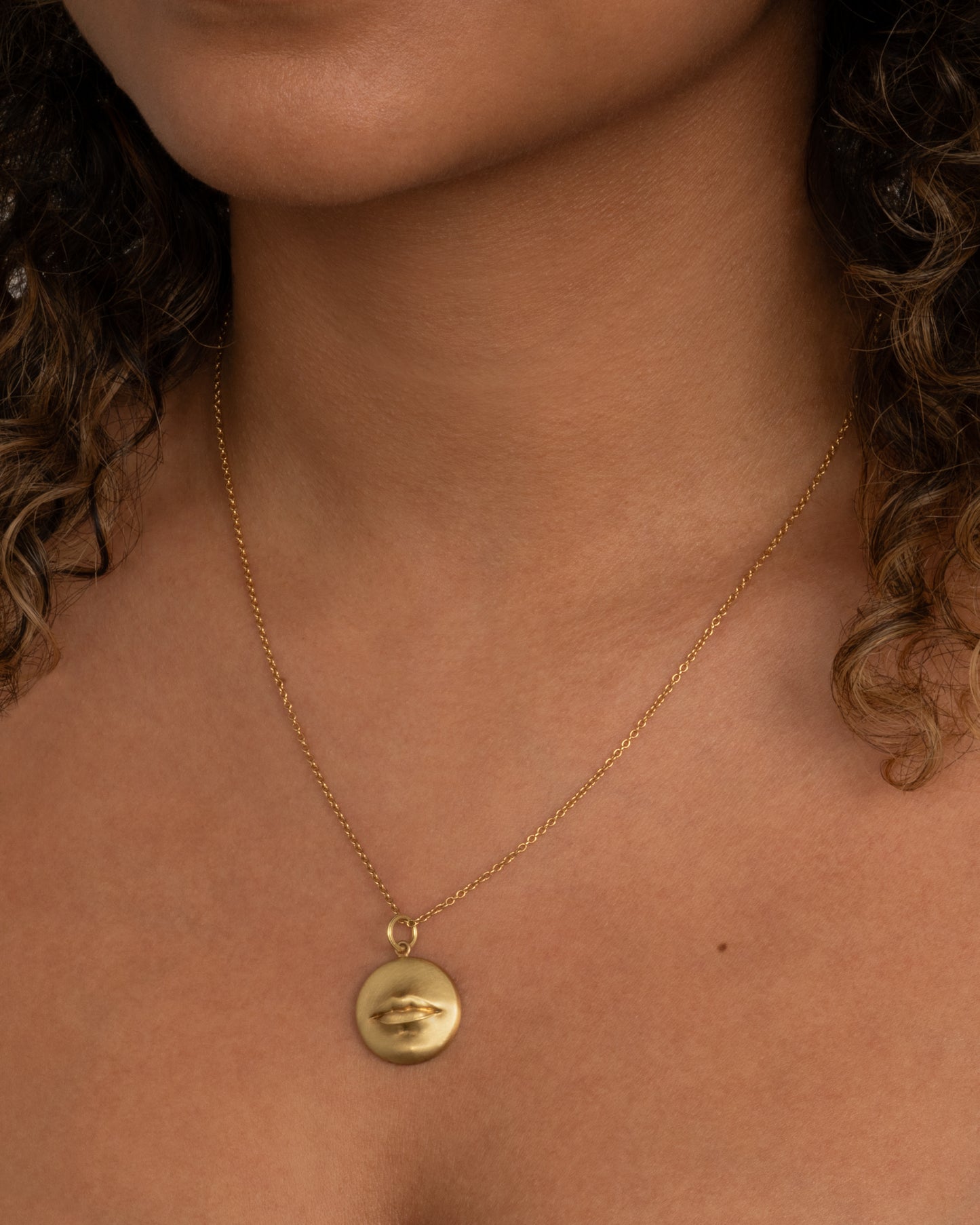 A solid, heavy pendant with a striking, sensual design with a sense of humor. Shown worn around the neck.